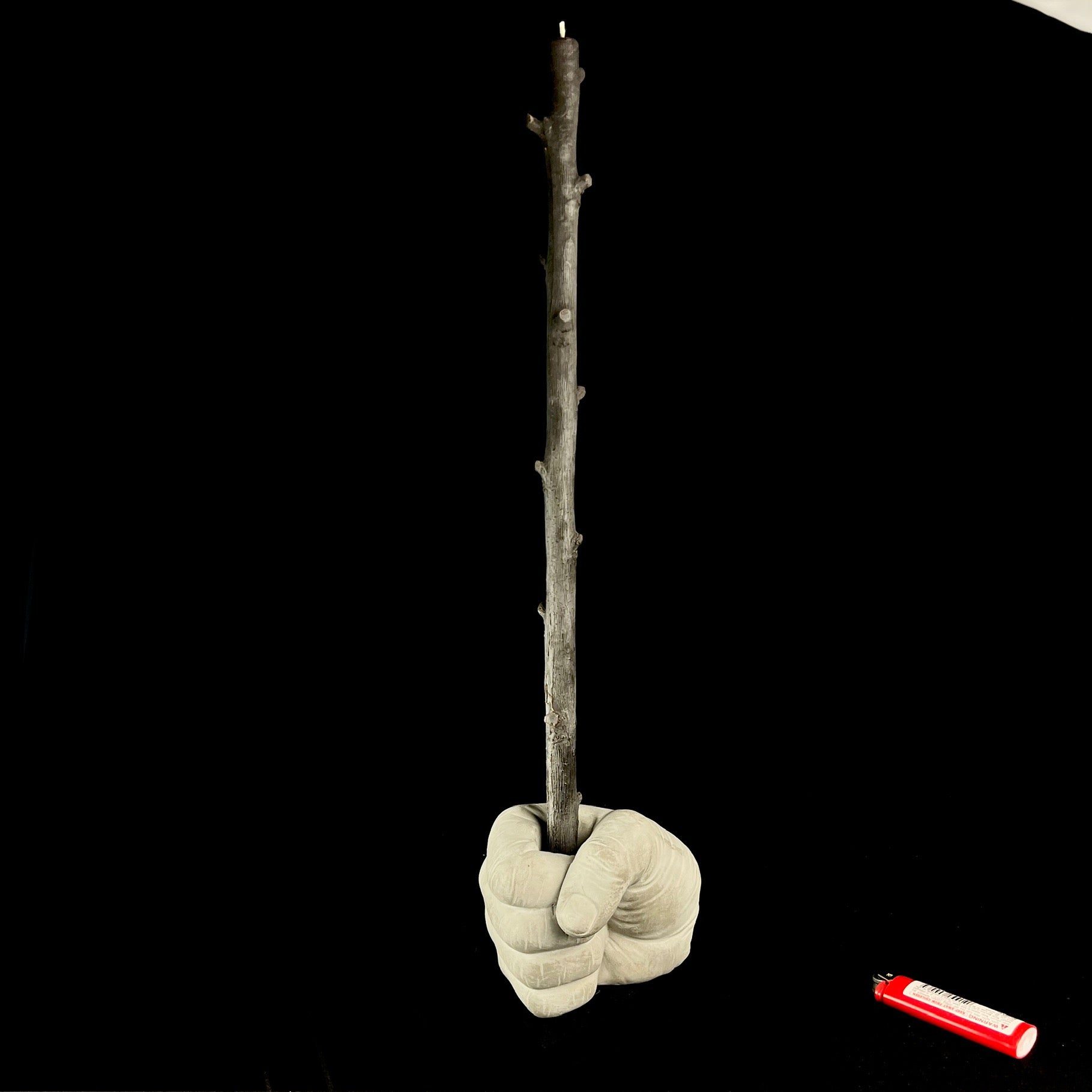 Light grey concrete fist holding brown candle