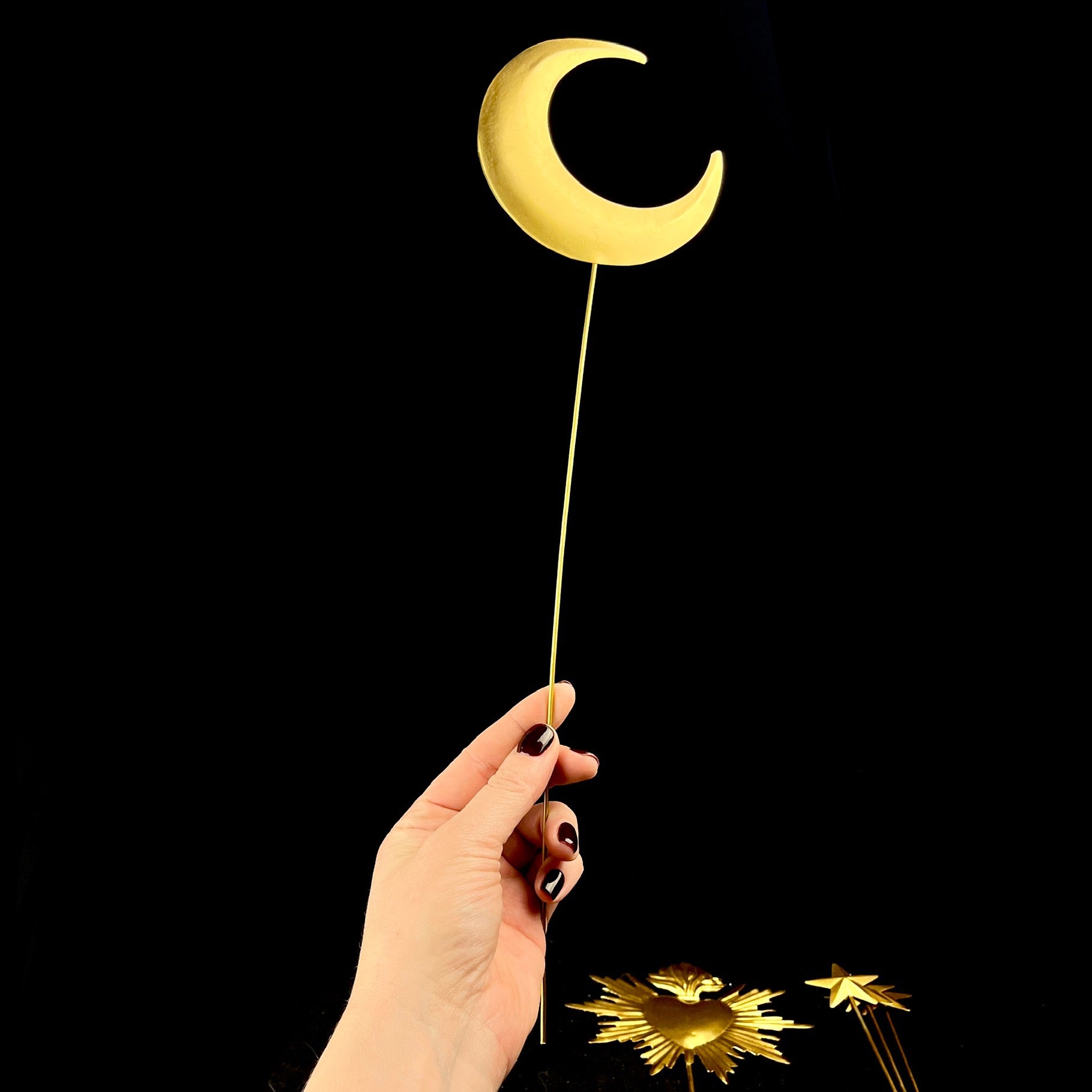 Golden Moon attached to long thin dowel shown held in hand