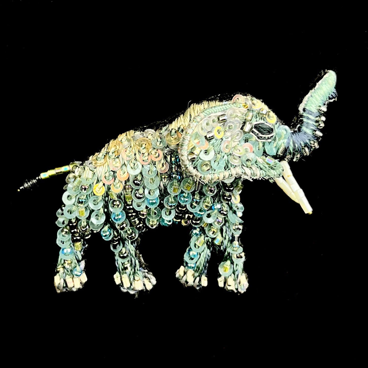 Walking elephant with upturned trunk and sparkling grey beads