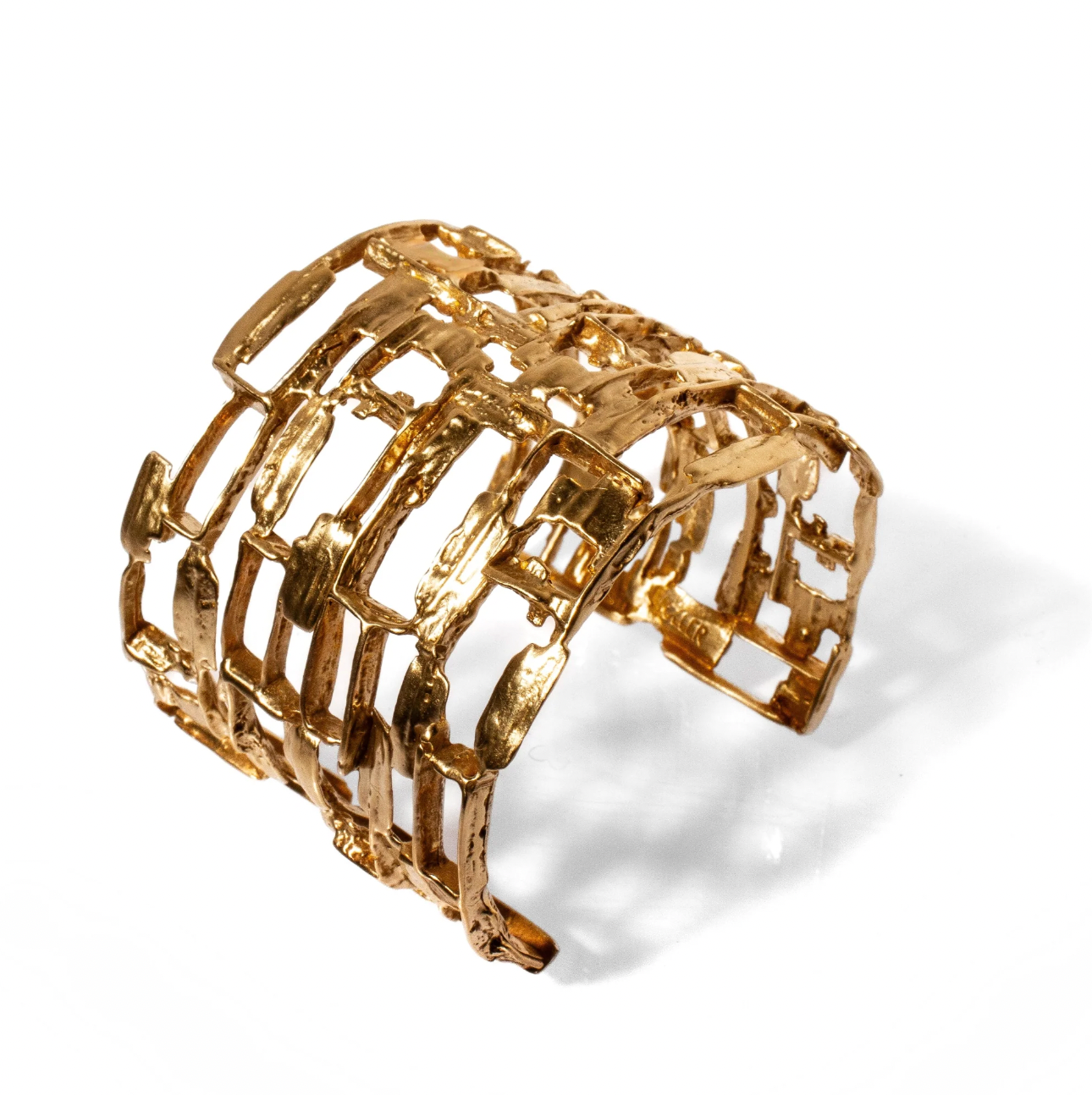 Gold bracelet with a textured design on a white background