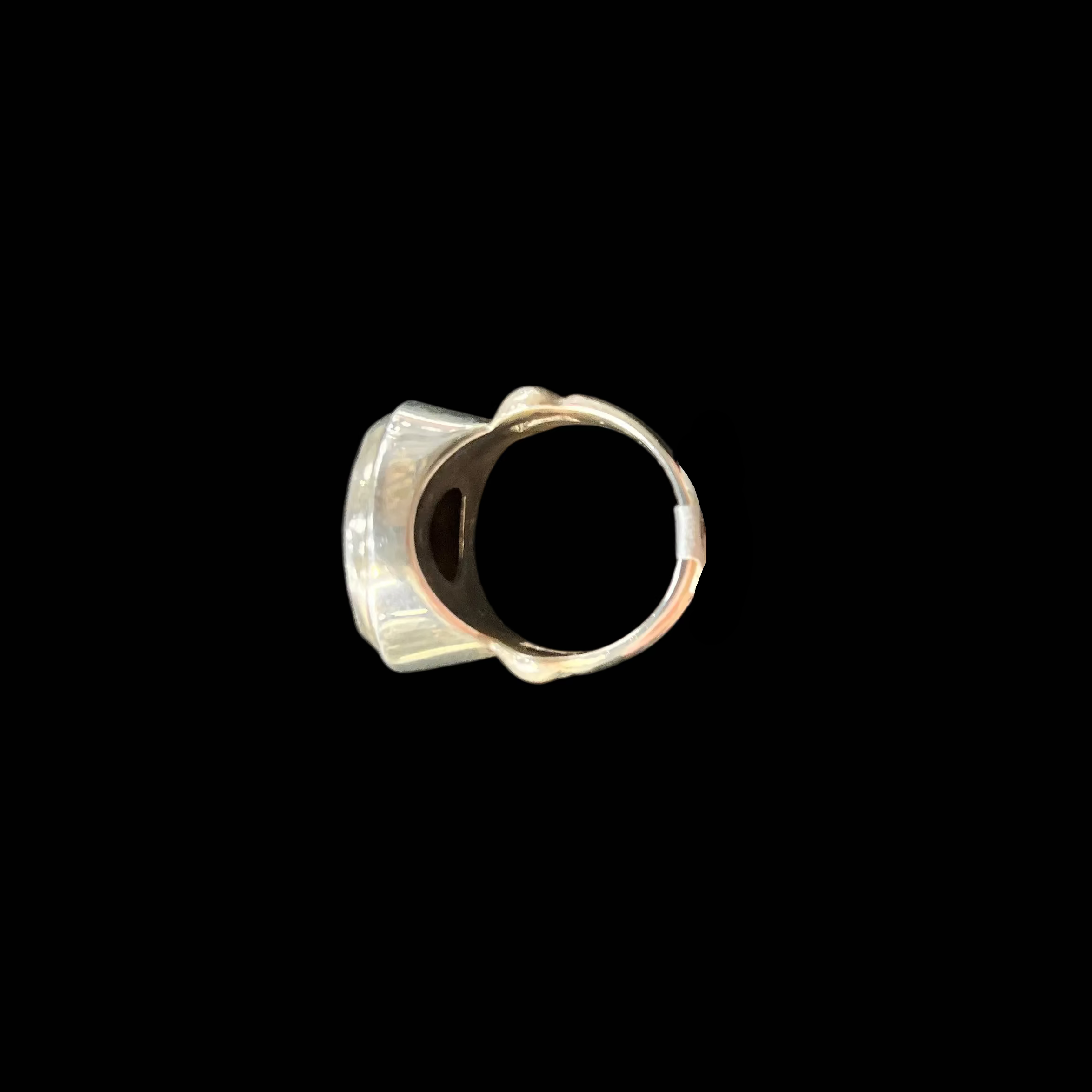 Hand holding a silver ring against a black background