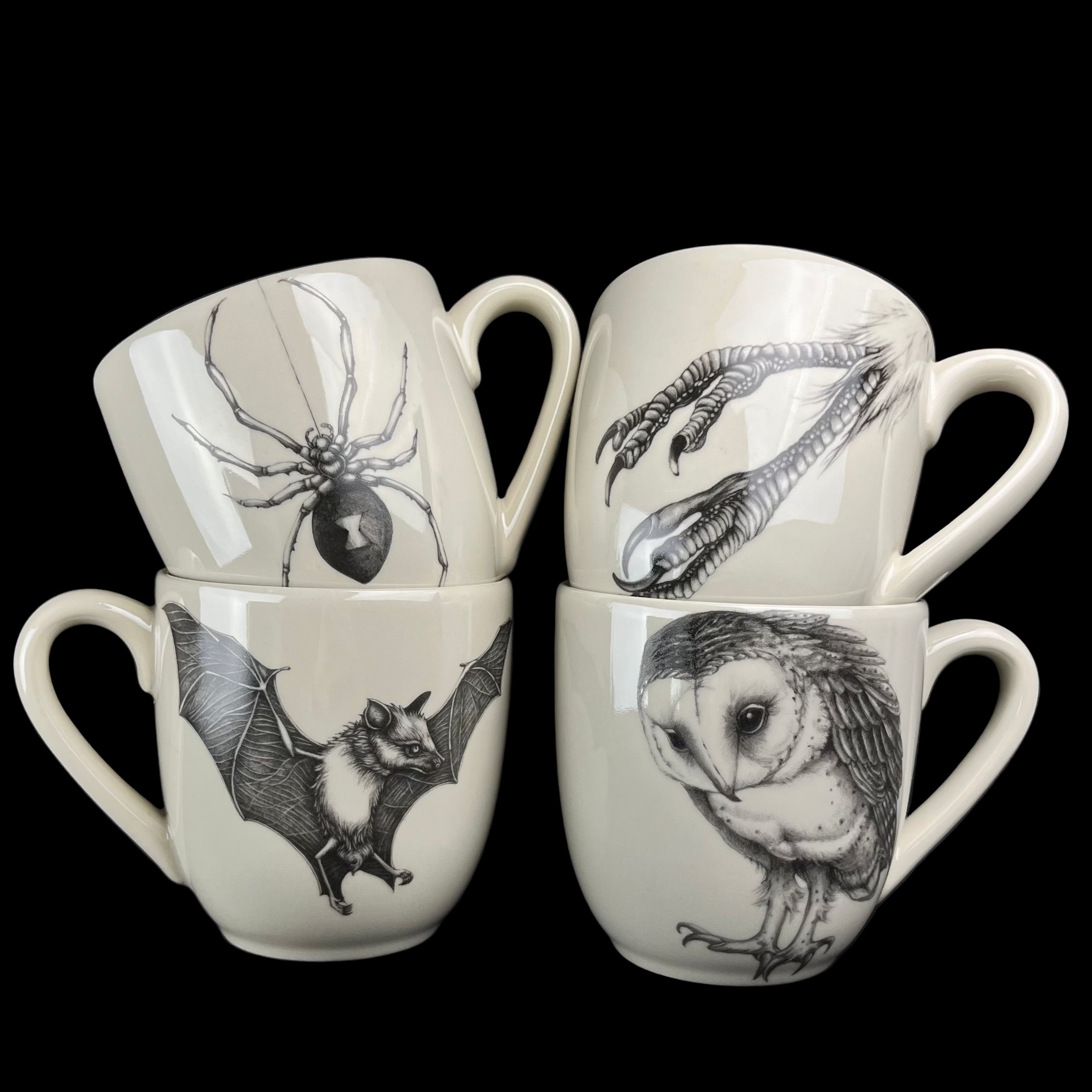 Four white mugs with black animal illustrations on a dark background