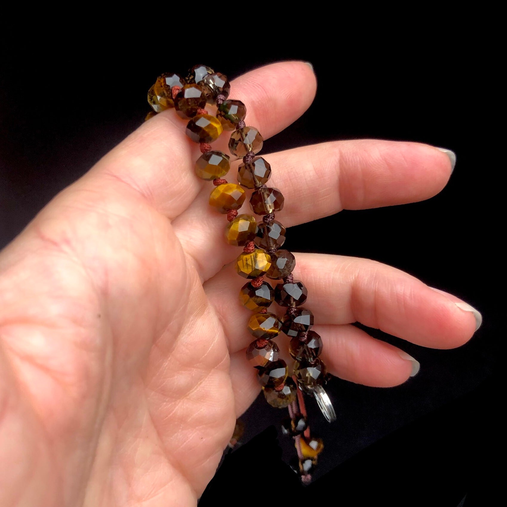 Golden brown and transparent grey beaded bracelet shown side by side in hand. 