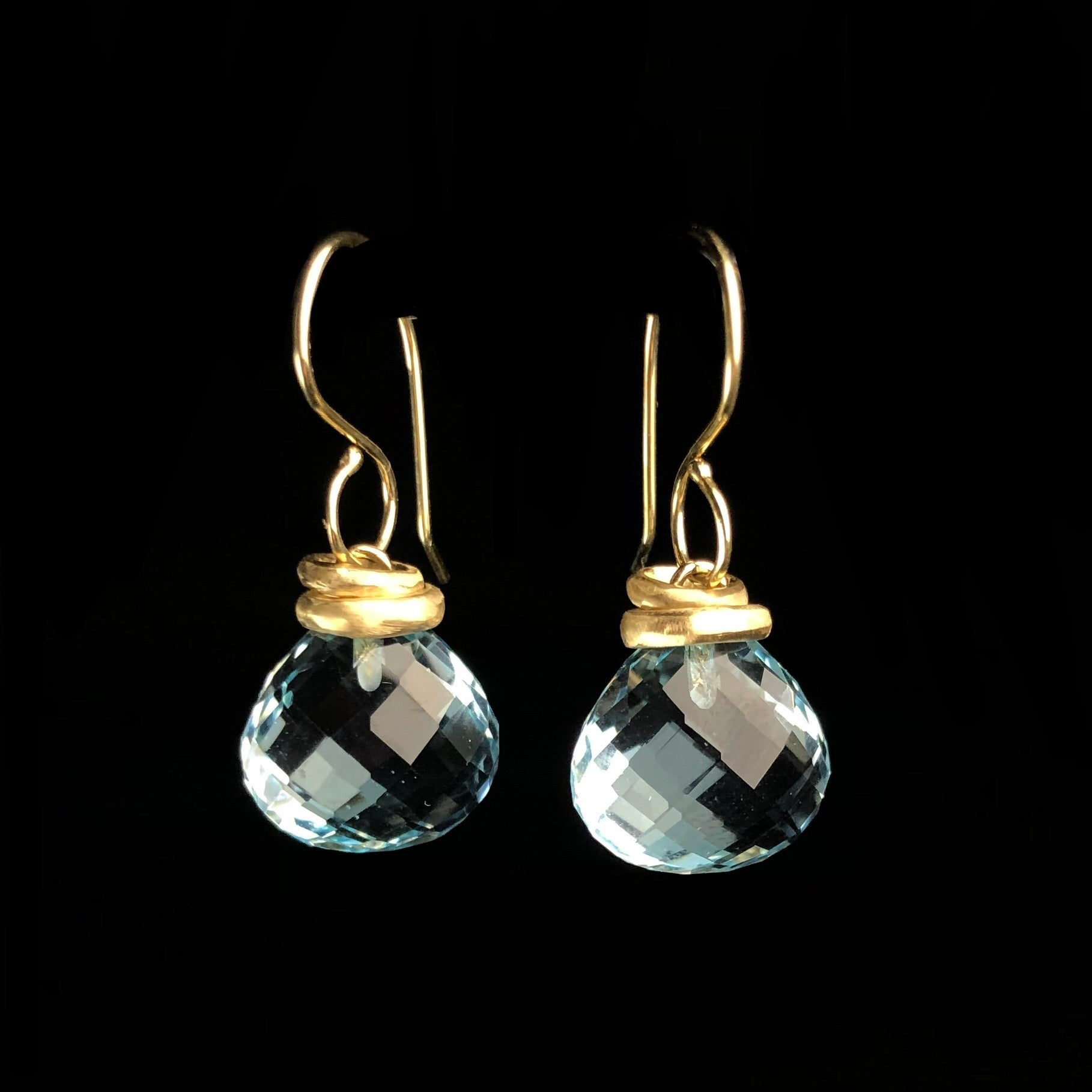 Transparent light blue stones hanging on gold earring hooks