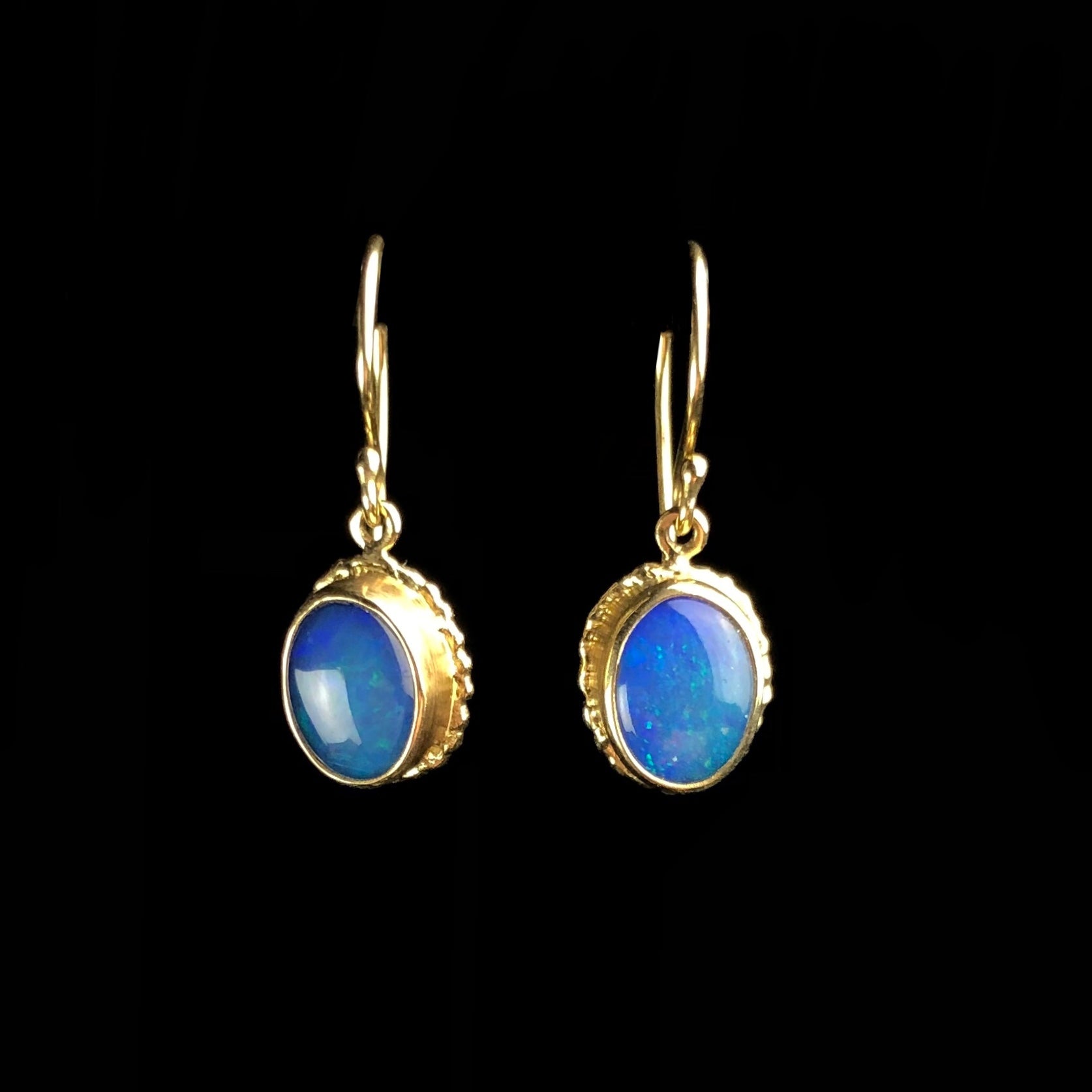 Oval blue and green opal stones hanging on gold earring wires