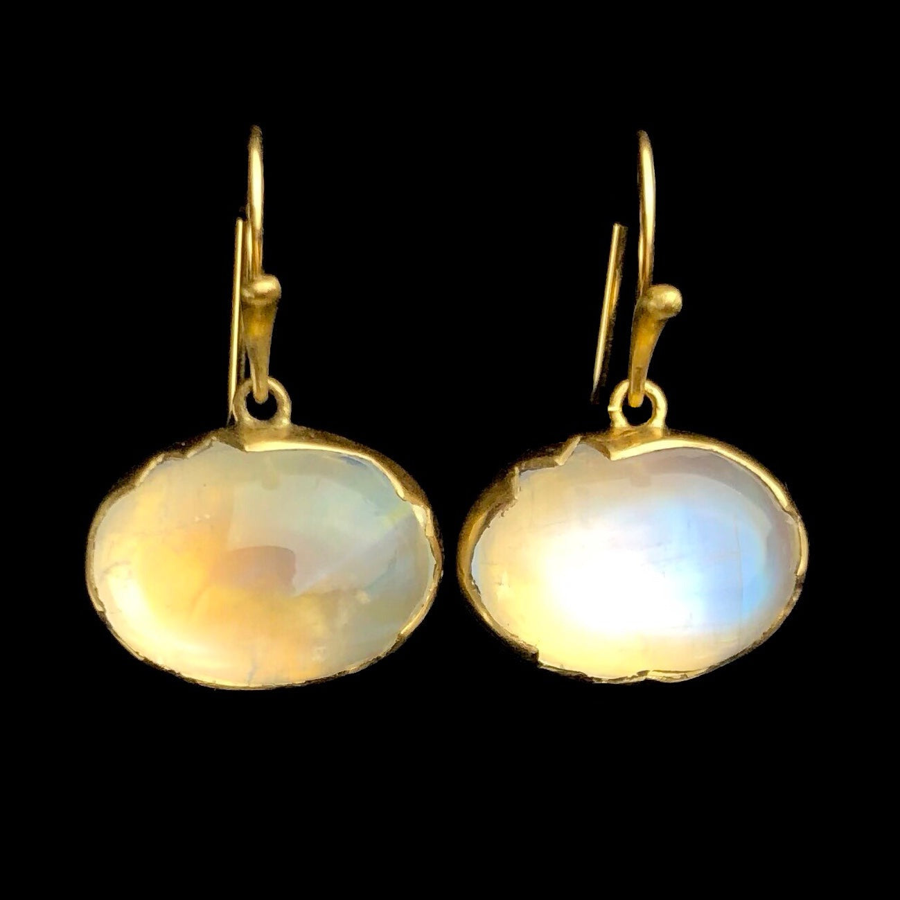 Sideways hanging oval moonstones glowing blue iridescence on gold earring wires 