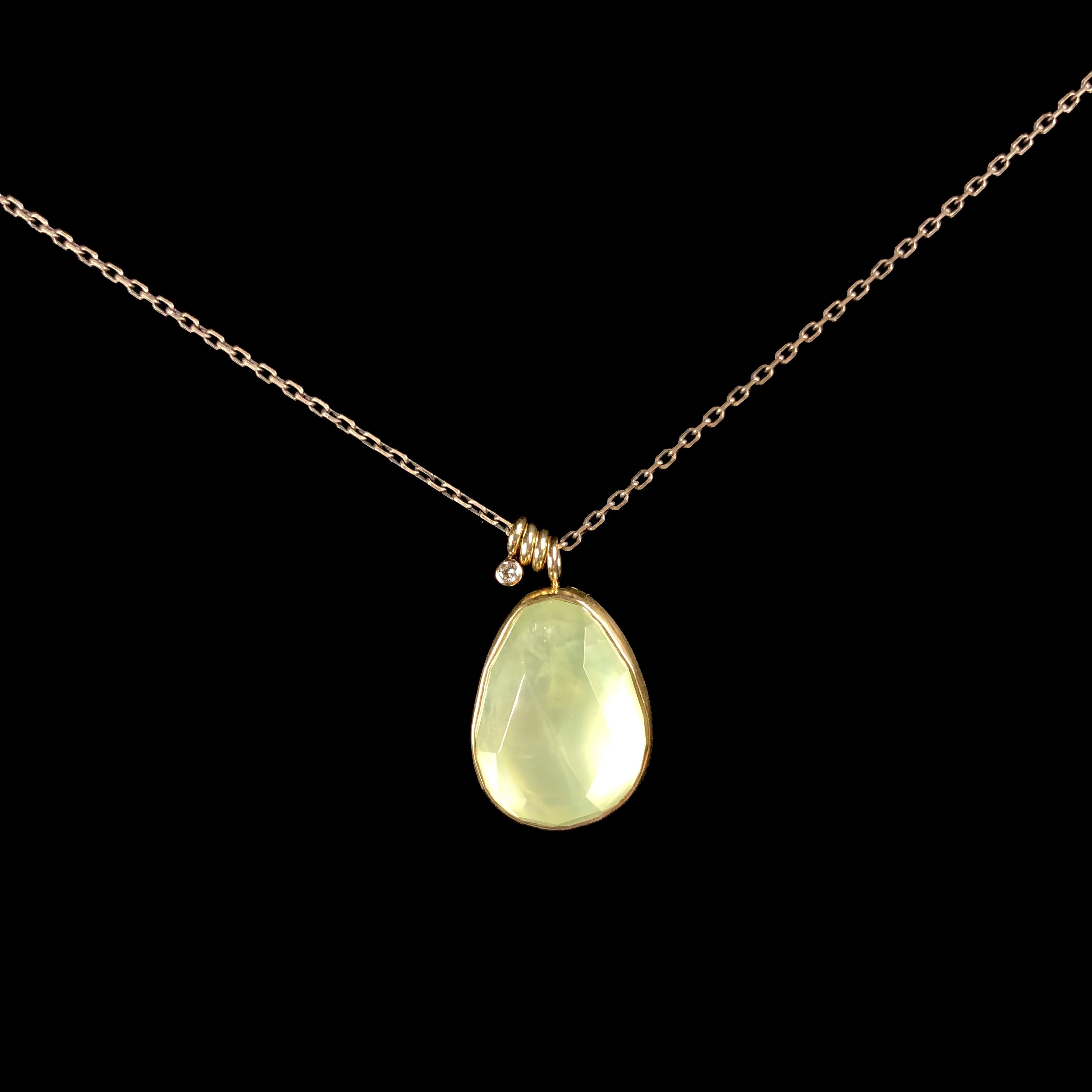 Light green teardrop shaped stone with gold setting on blackened silver chain