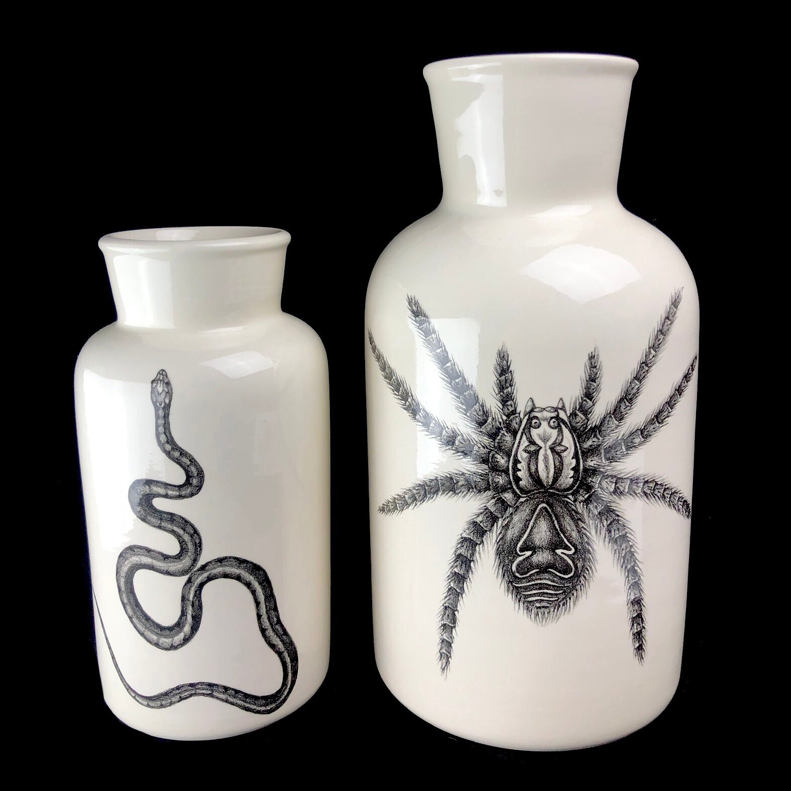 Large and Medium sized white vases with black drawings of a snake and a tarantula.