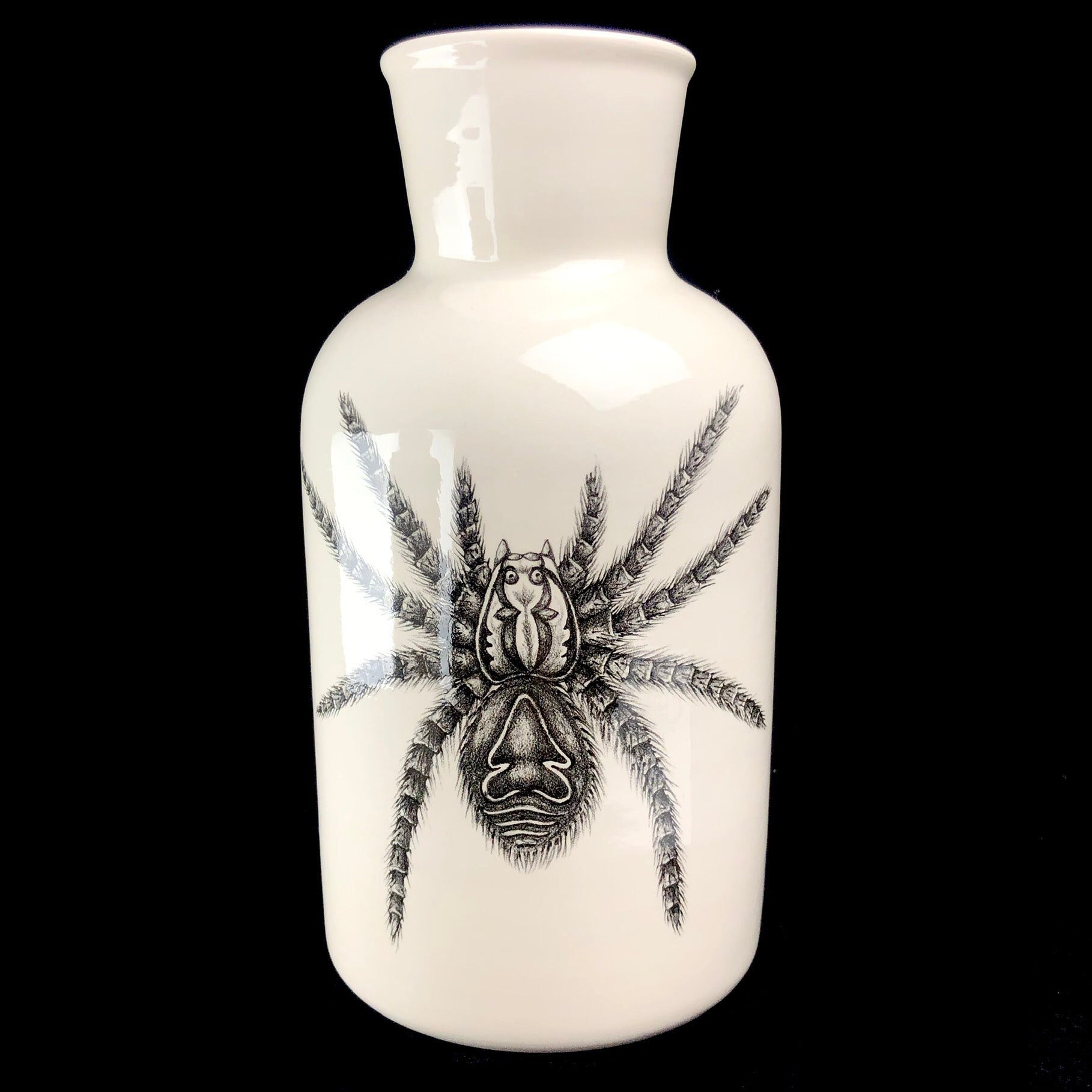 White vase with black drawing of tarantula covering its front