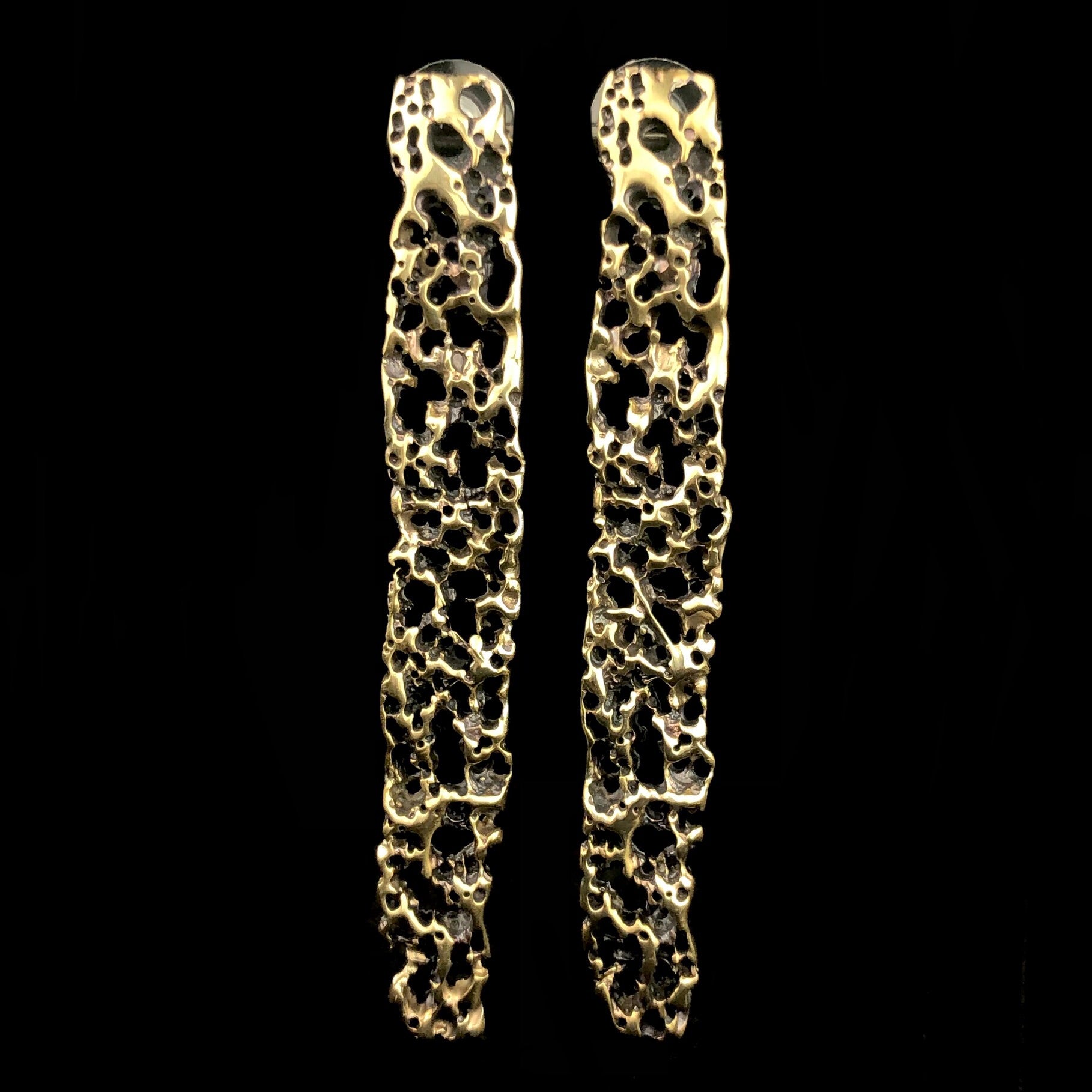 Front view of Atoll Vertical Earrings with black background showing throw open spaces in brass