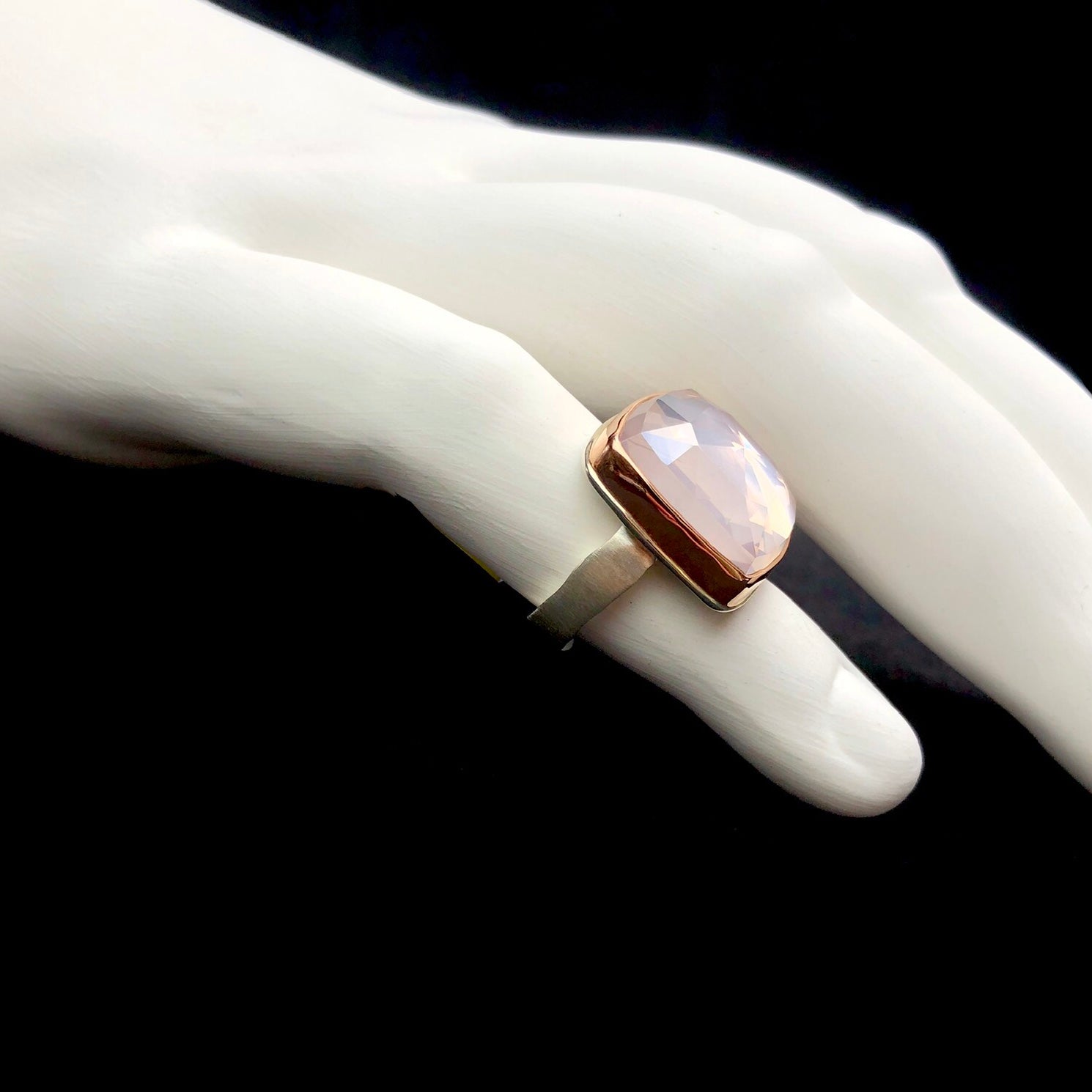 Side profile view of rose gold setting and silver band design on white ceramic finger