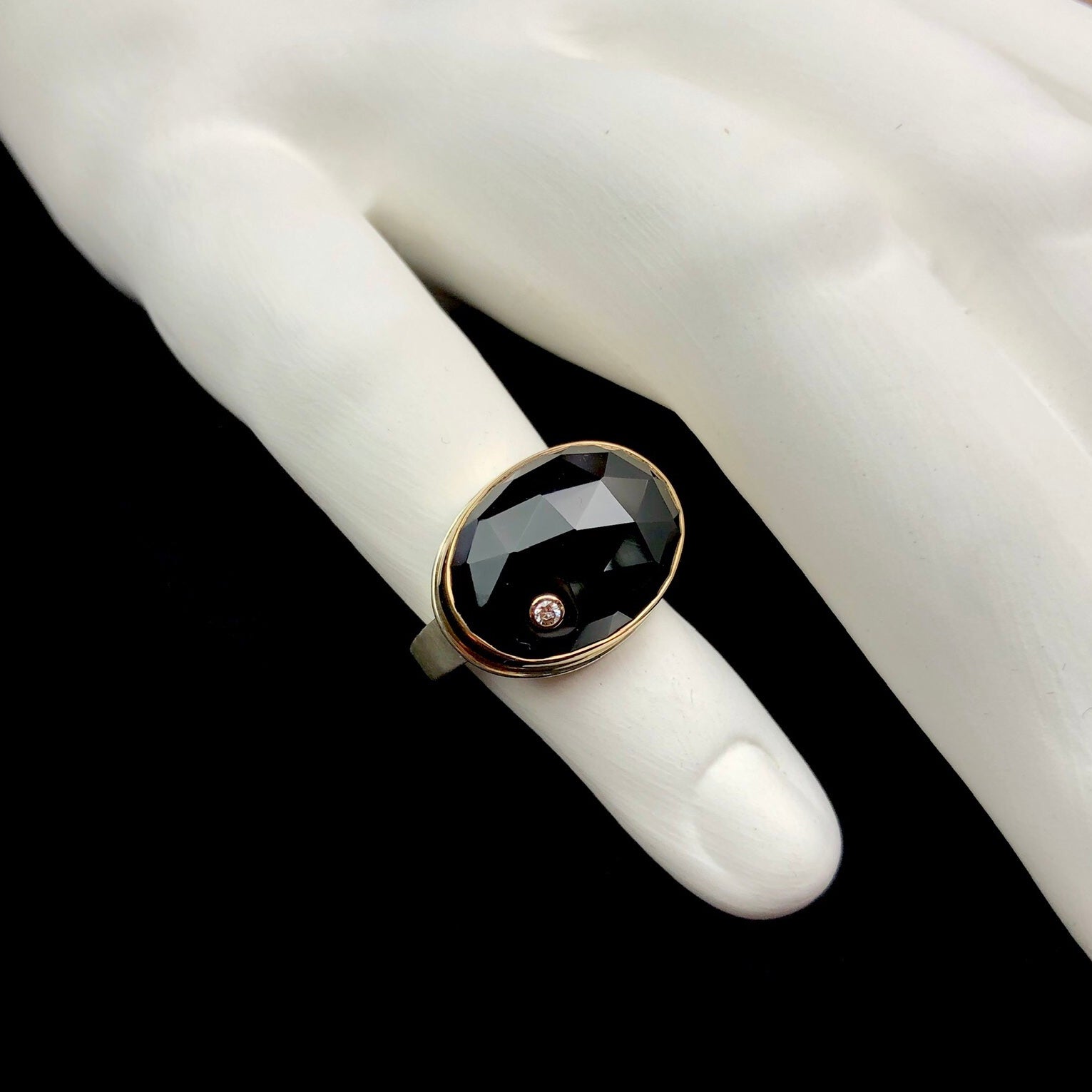 Top view of oval shaped black onyx ring with diamond accent