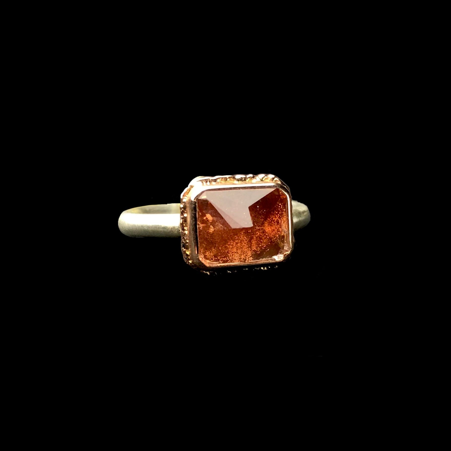 Front side view of orange Oregon sunstone ring with glimmering flex inside