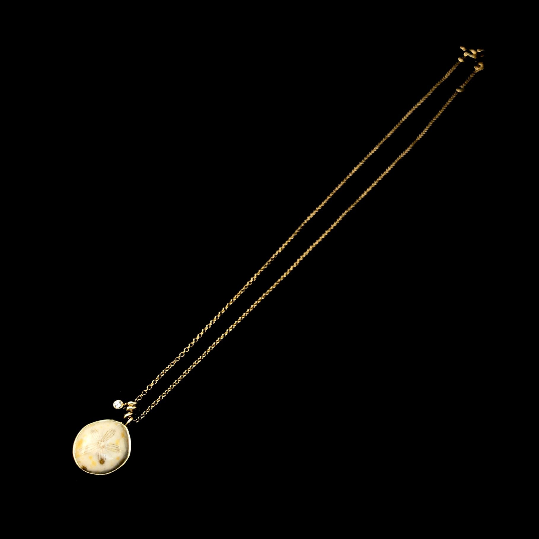 Side view of Fossilized Sea Urchin Necklace with diamond accent detail