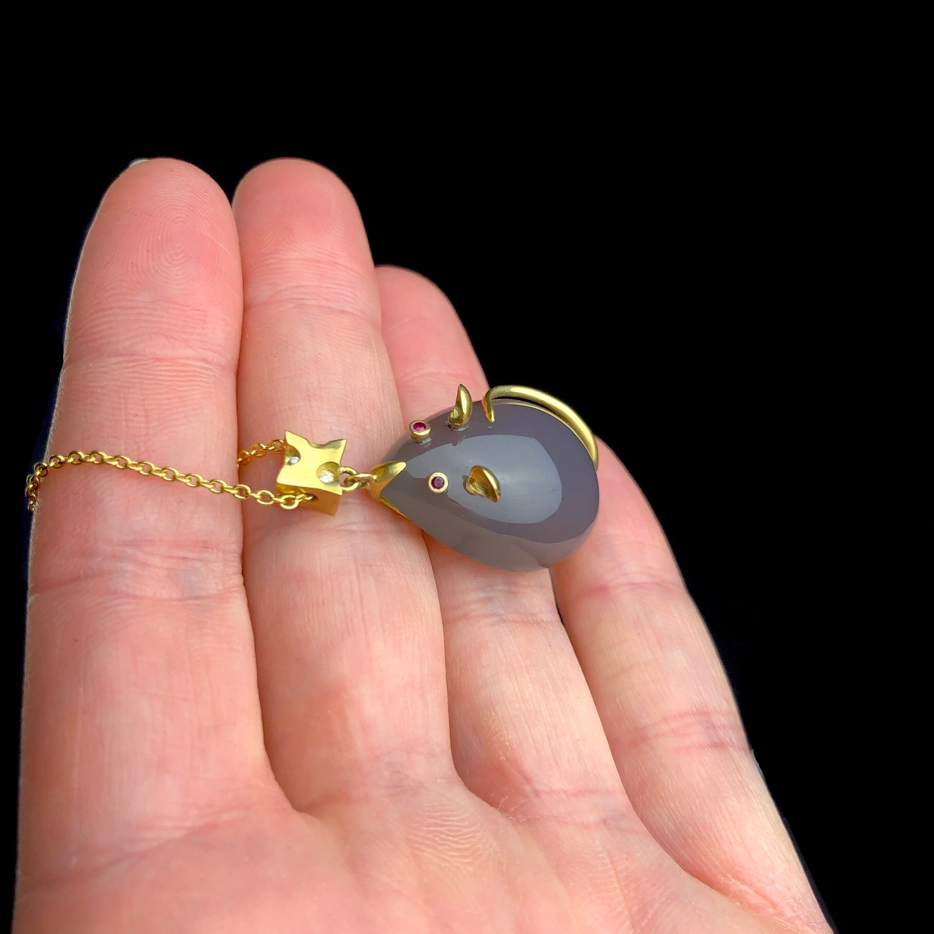 Side view of Mouse pendant attached to gold cheese block with diamond accents show in hand