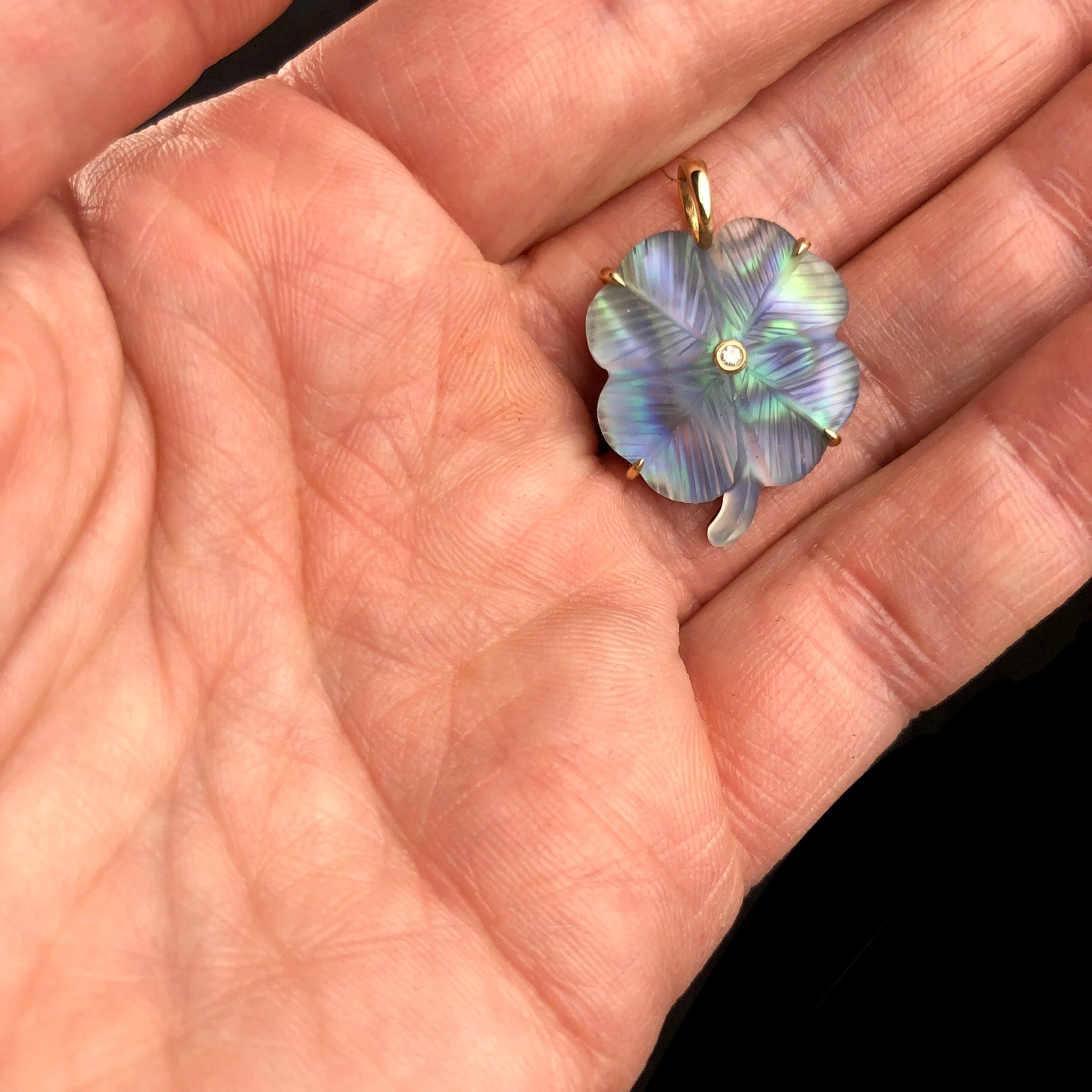 Luminescent Clover Charm shown in hand for size reference