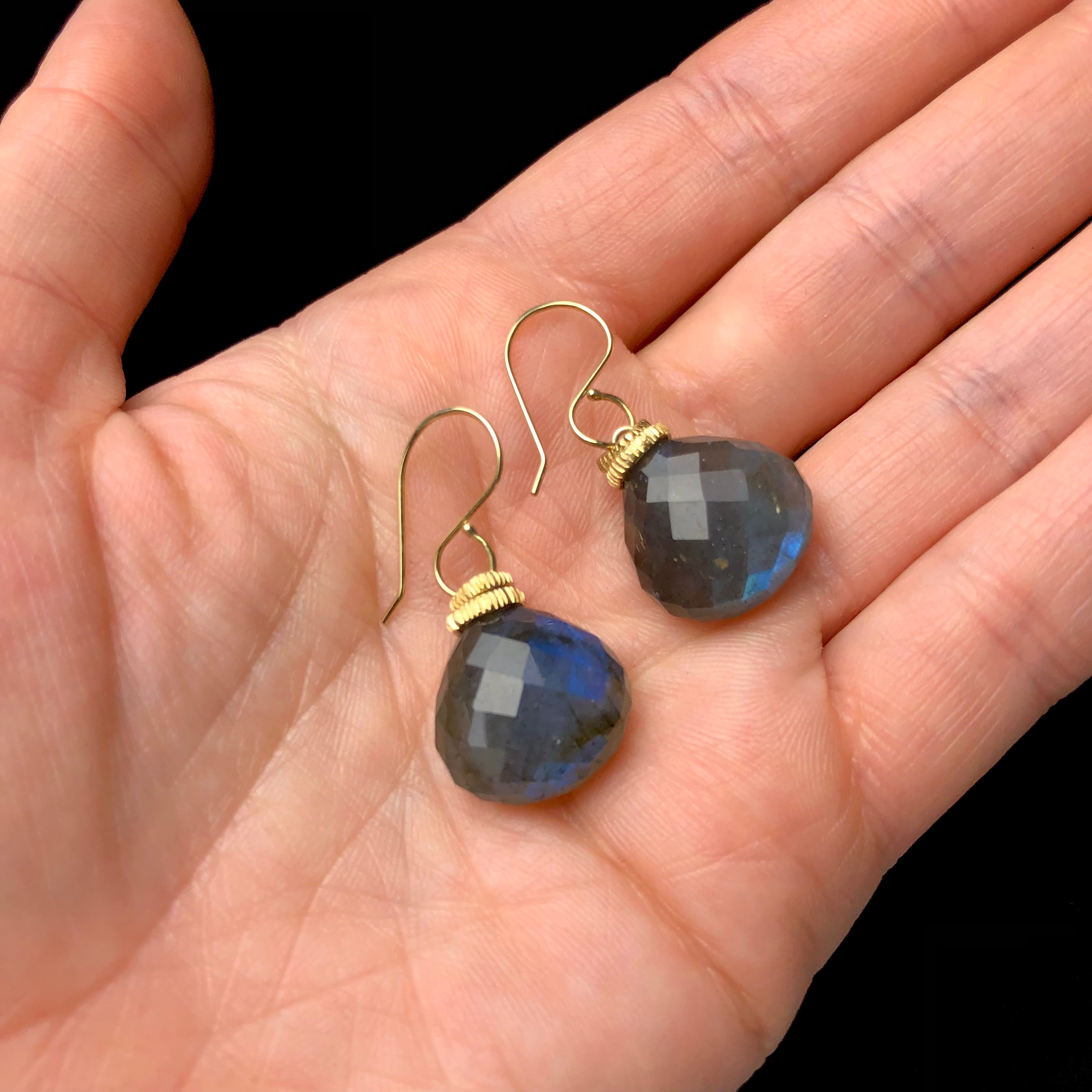 Plump Labradorite Earrings shown in hand with iridescent blue glow from within