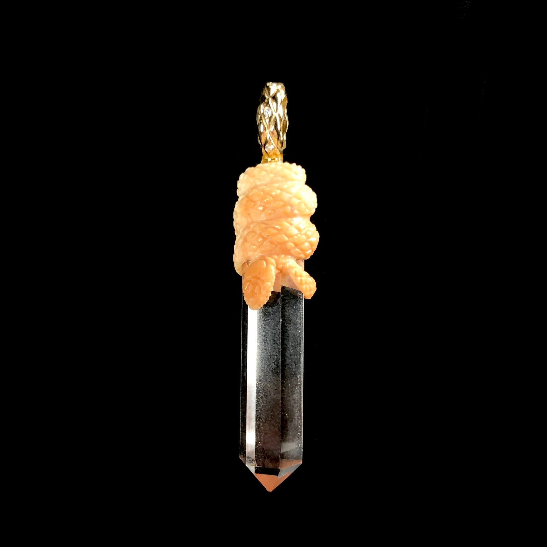 Clear crystal with light orange snake coiled about its top with gold bail