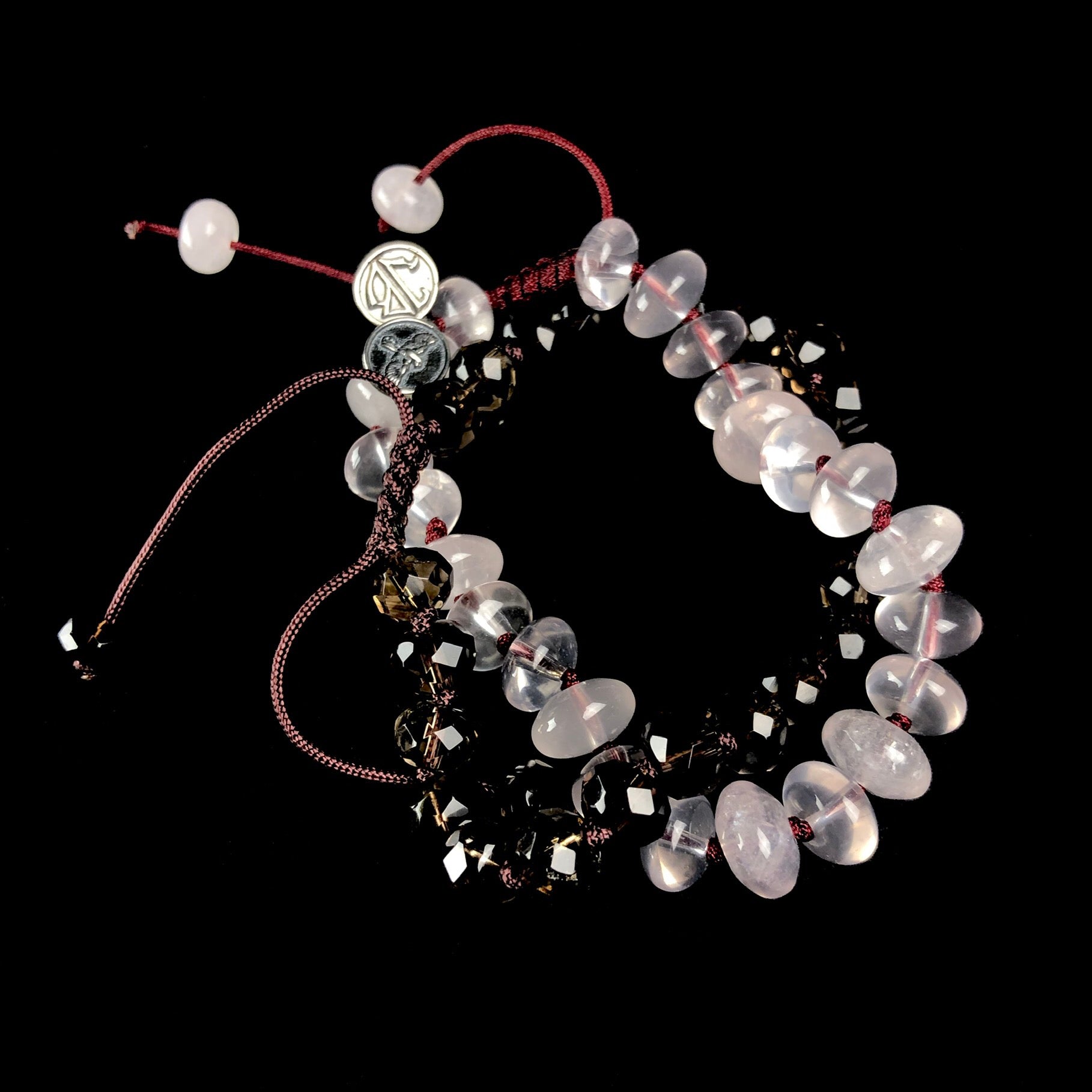 Translucent light pink colored stone bracelet with dark grey faceted stone bracelet on knotted cords