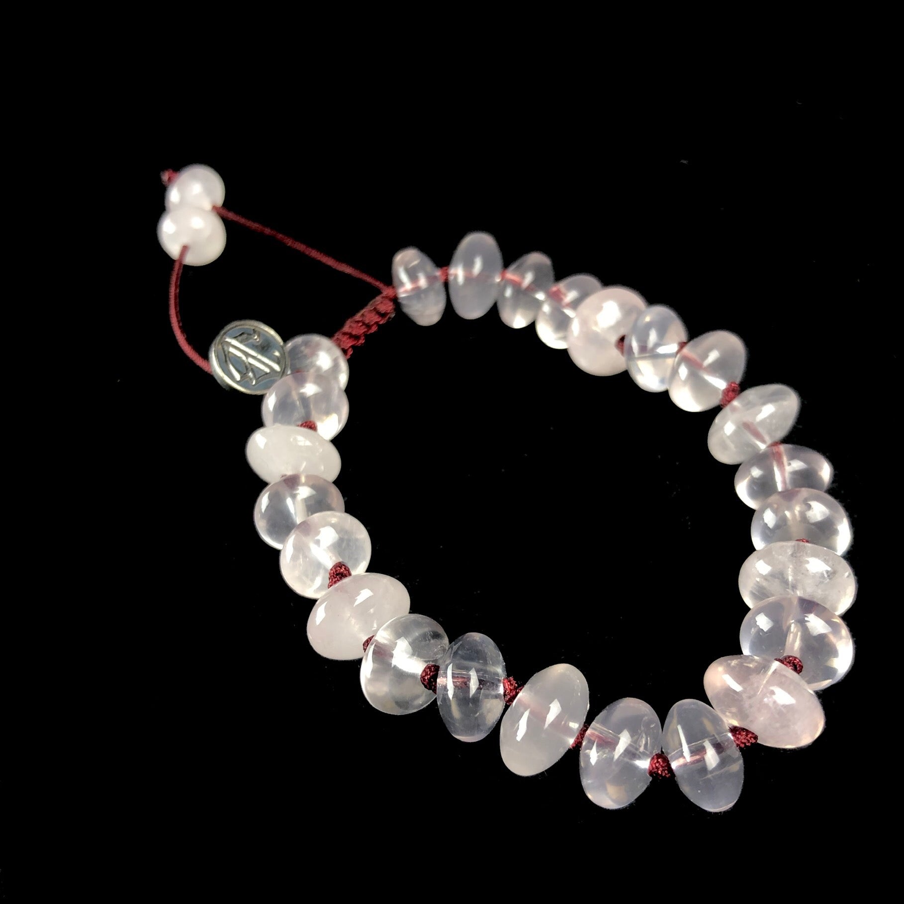 Translucent light pink colored stones bracelet on dark red knotted cord
