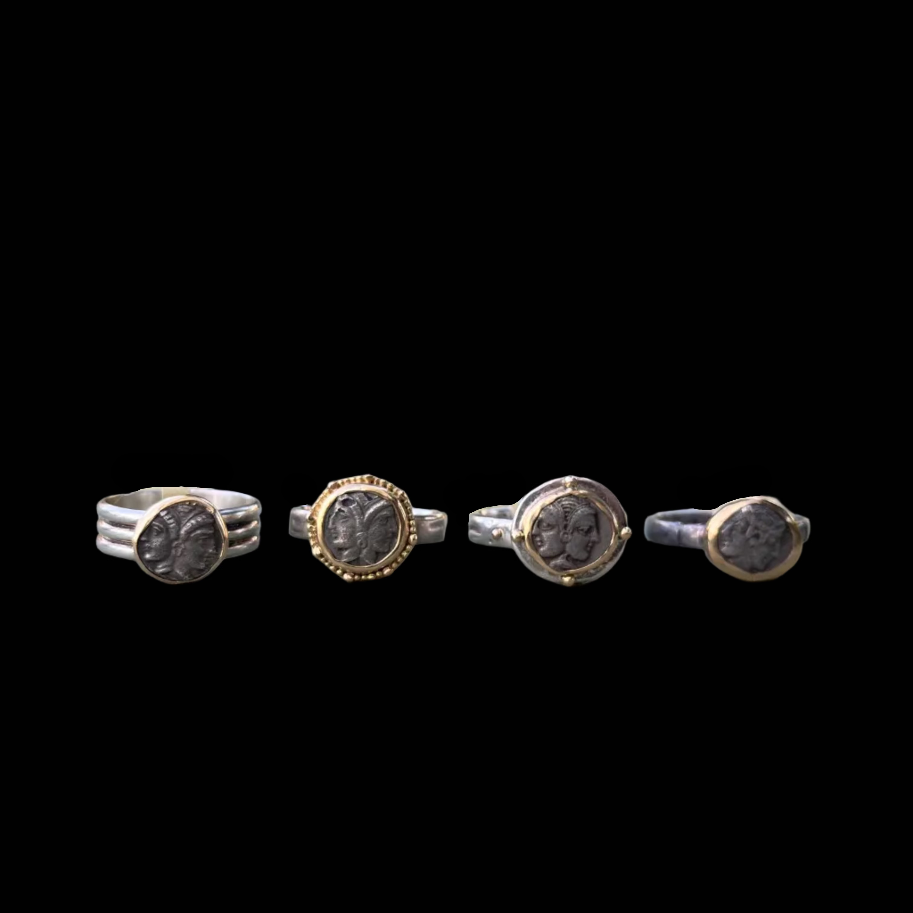 Four rings with circular designs on a textured surface outdoors.
