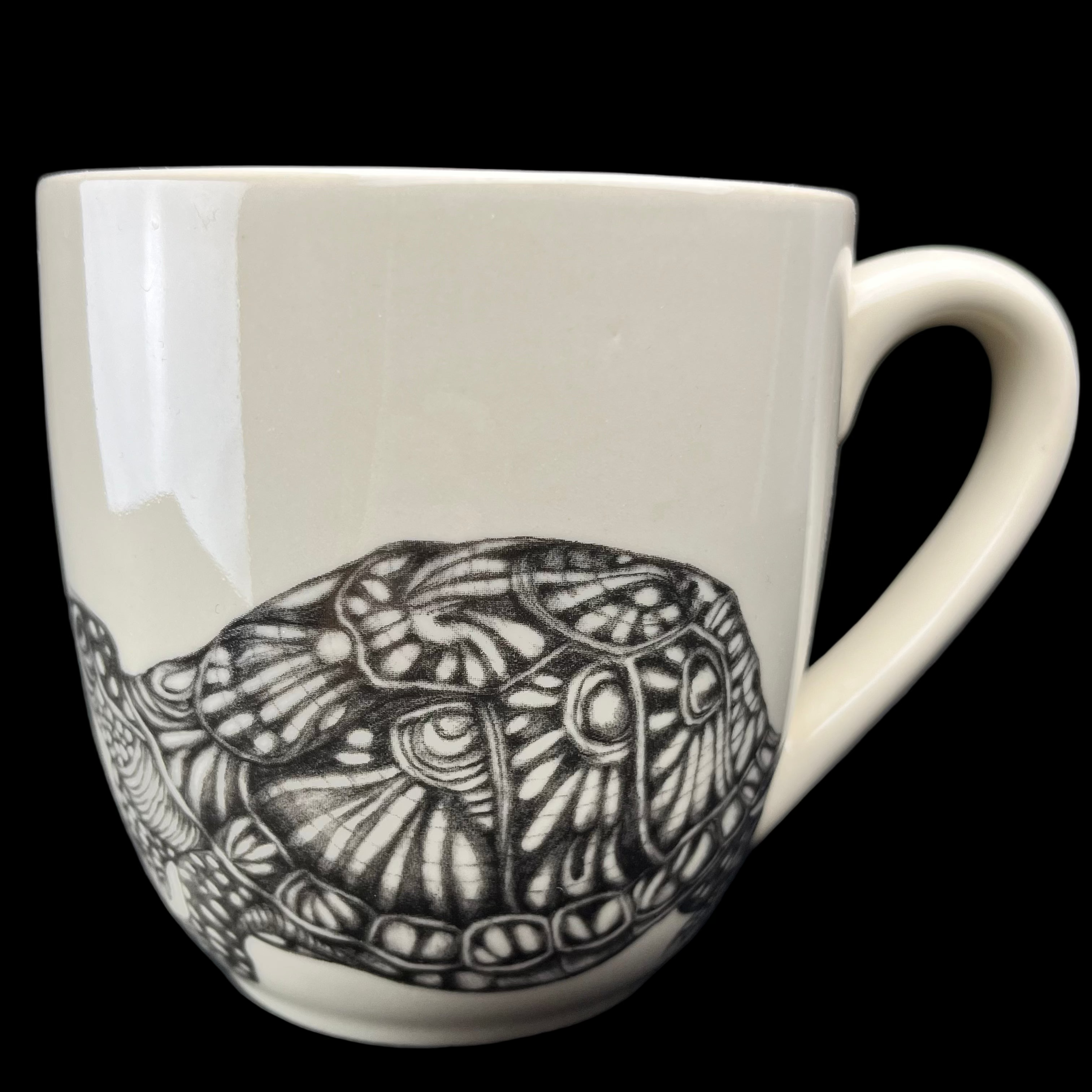 White mug with black turtle design on a dark background