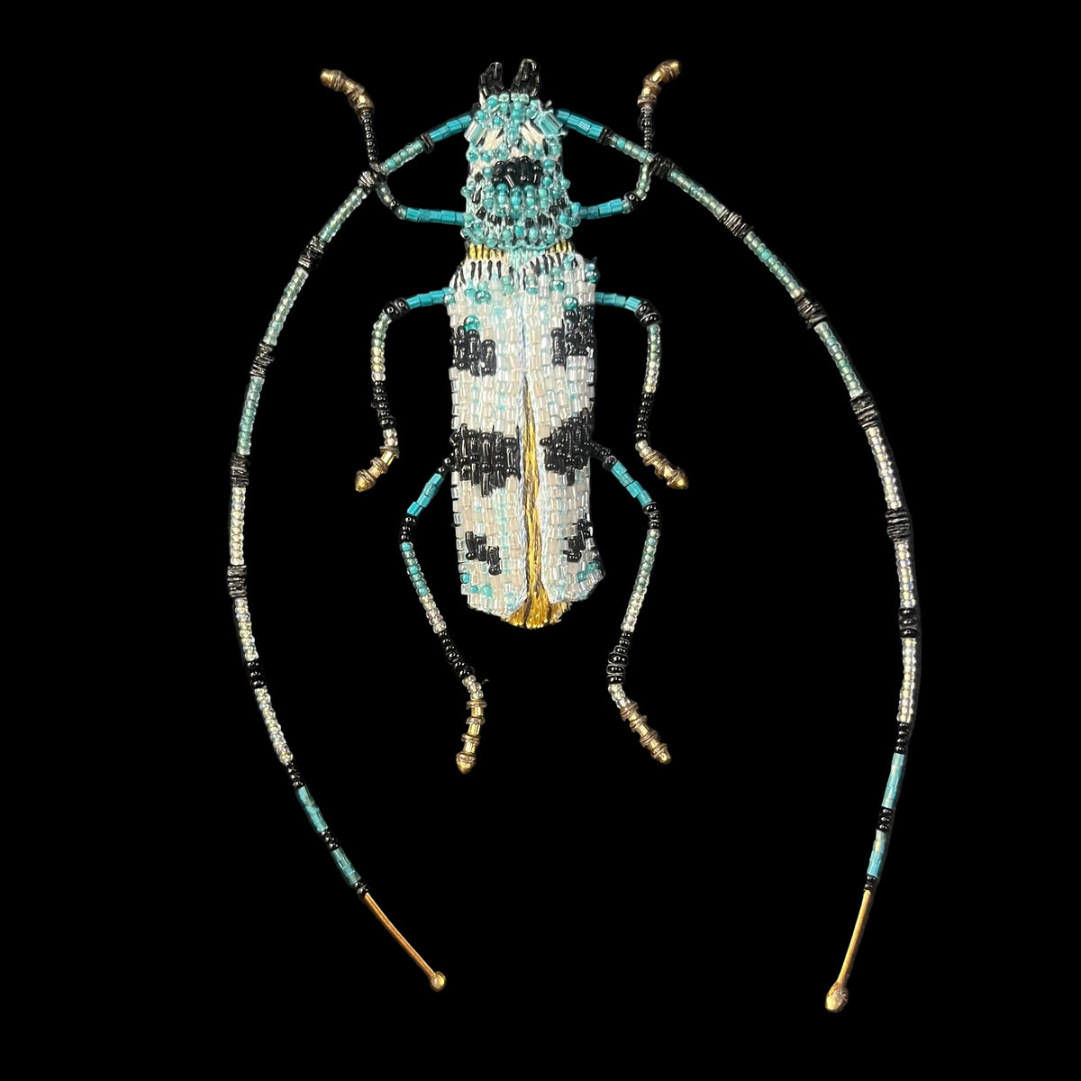 Intricately beaded blue and white glass in lifelike patterns found on longhorn beetles with long antenna.