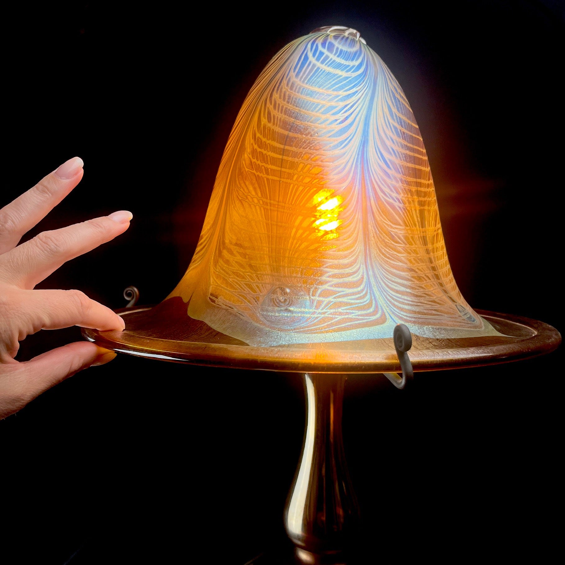 Glass sculpture with a hand holding it against a dark background