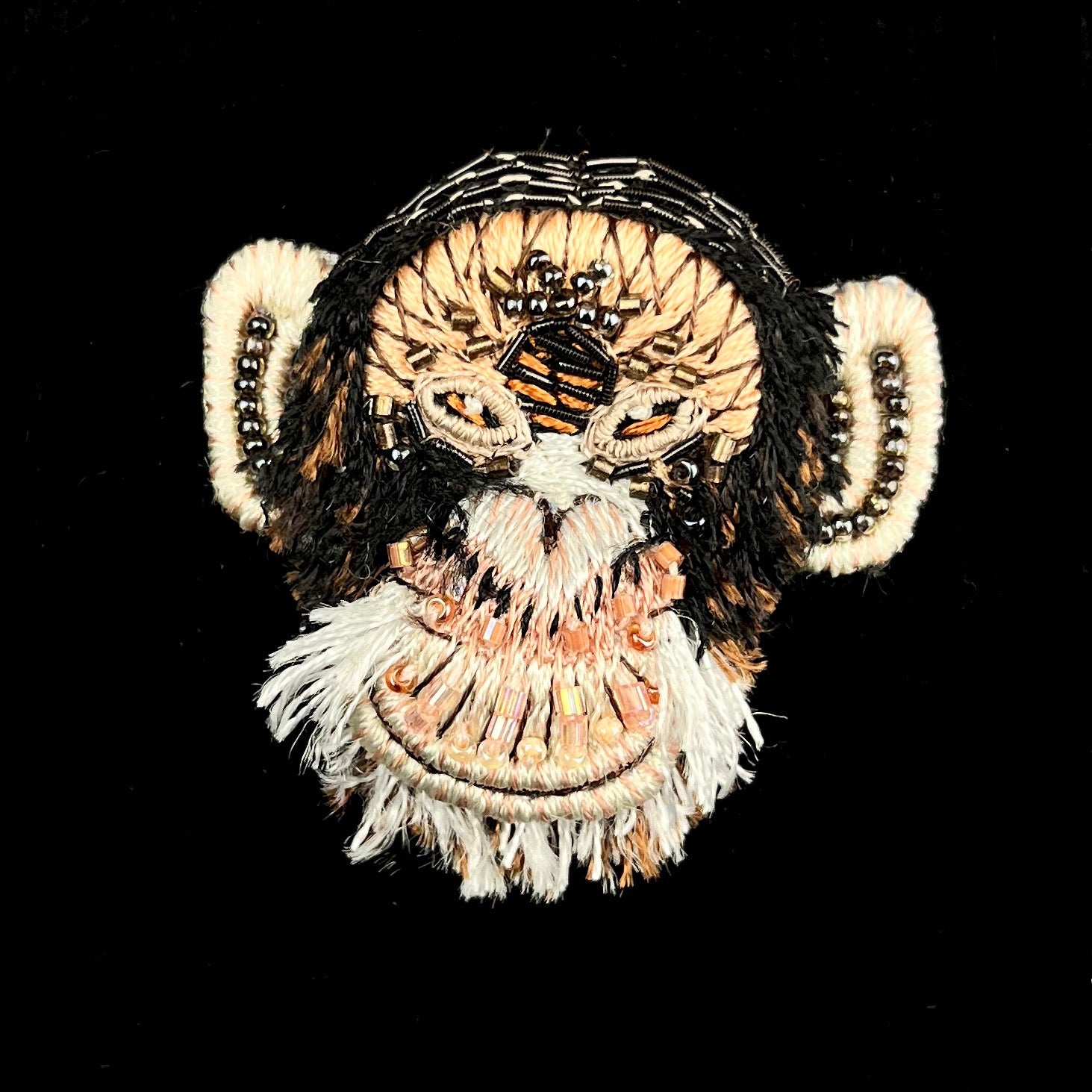 Tan, dark brown and white furry thread and sparkling glass beads create this smiling monkey face