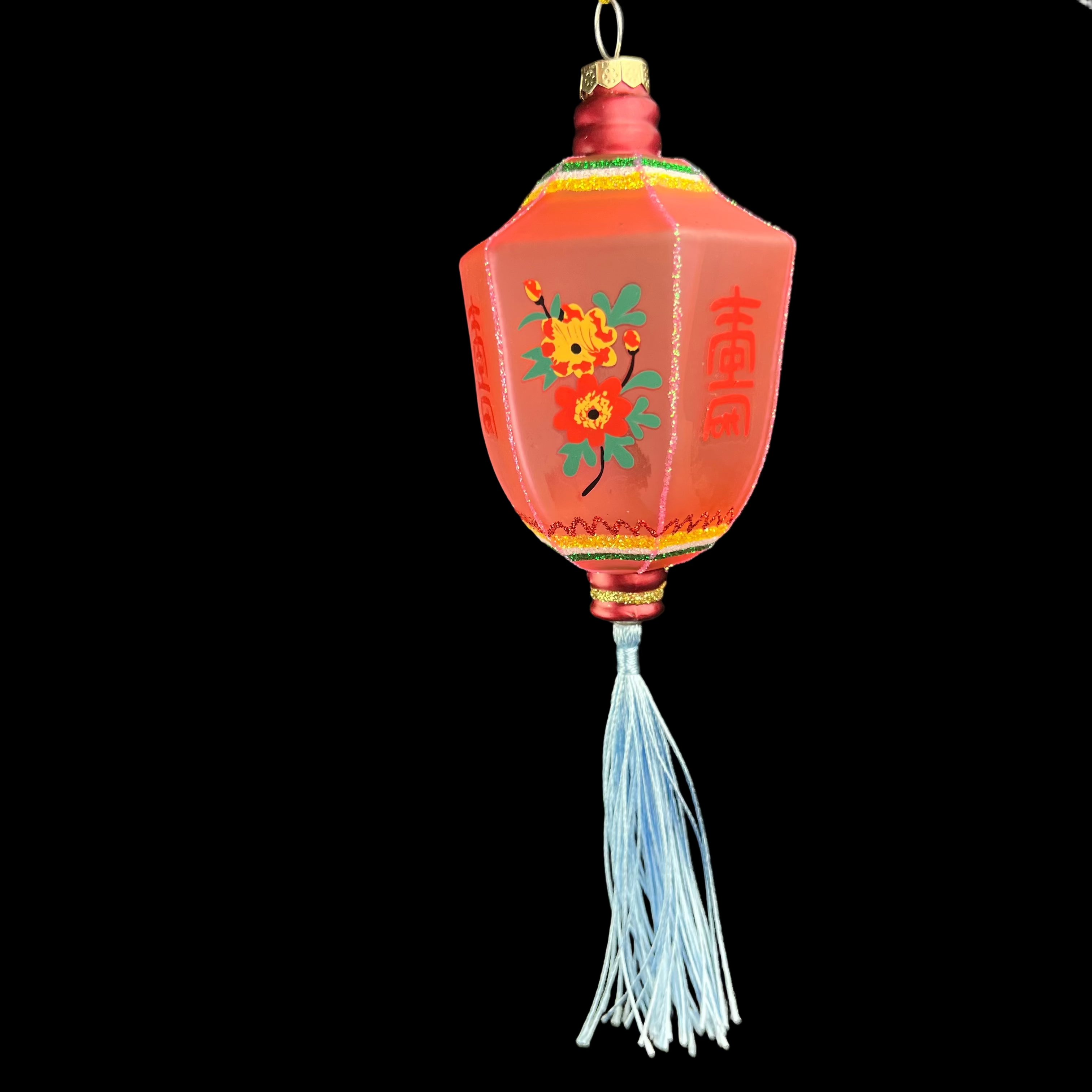 Decorative red lantern with floral design and tassel on a black background