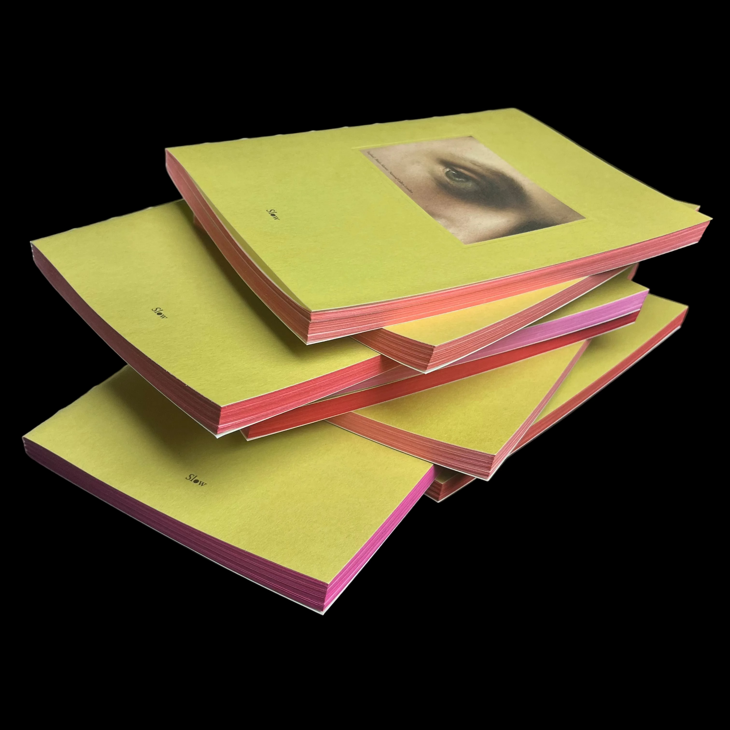 Stack of green and pink books on a dark surface