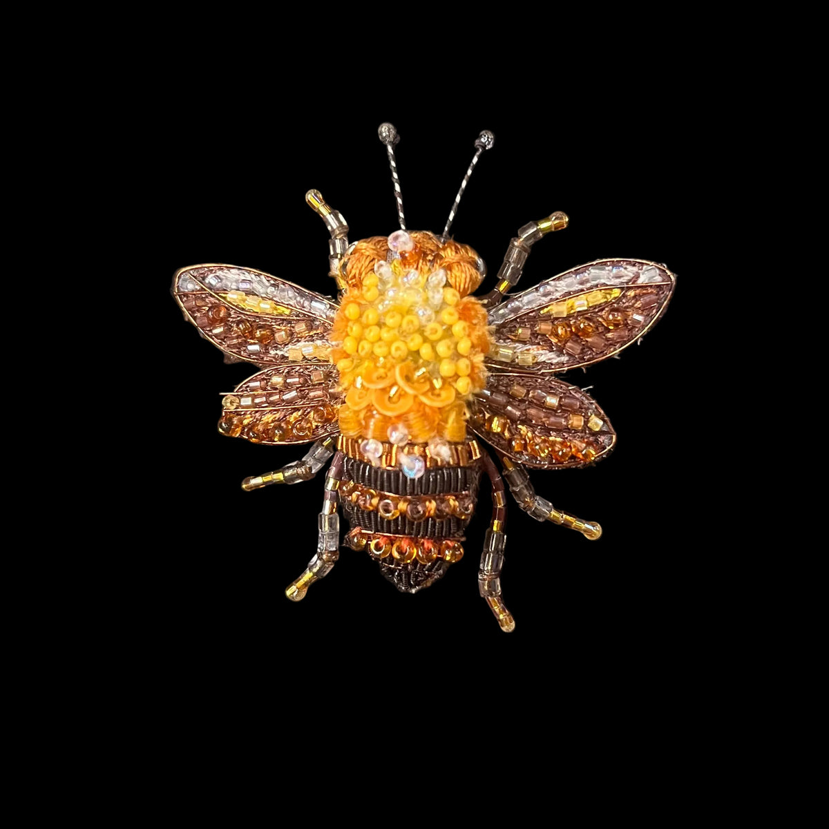An embroidered bee with glass beads that crest a lifelike feel
