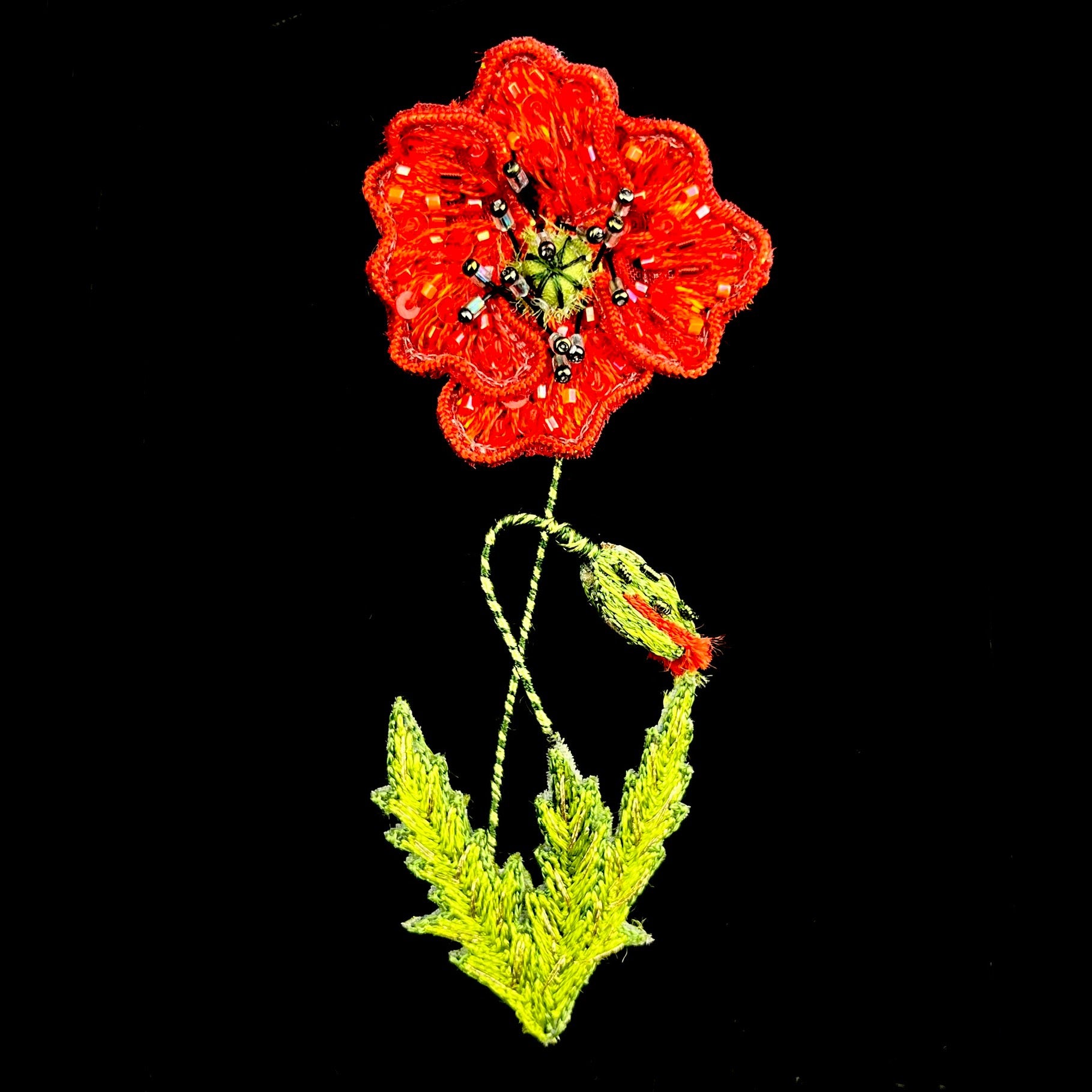 An open poppy flower with red threaded pedals adorned with shimmering bead accents and a green stem
