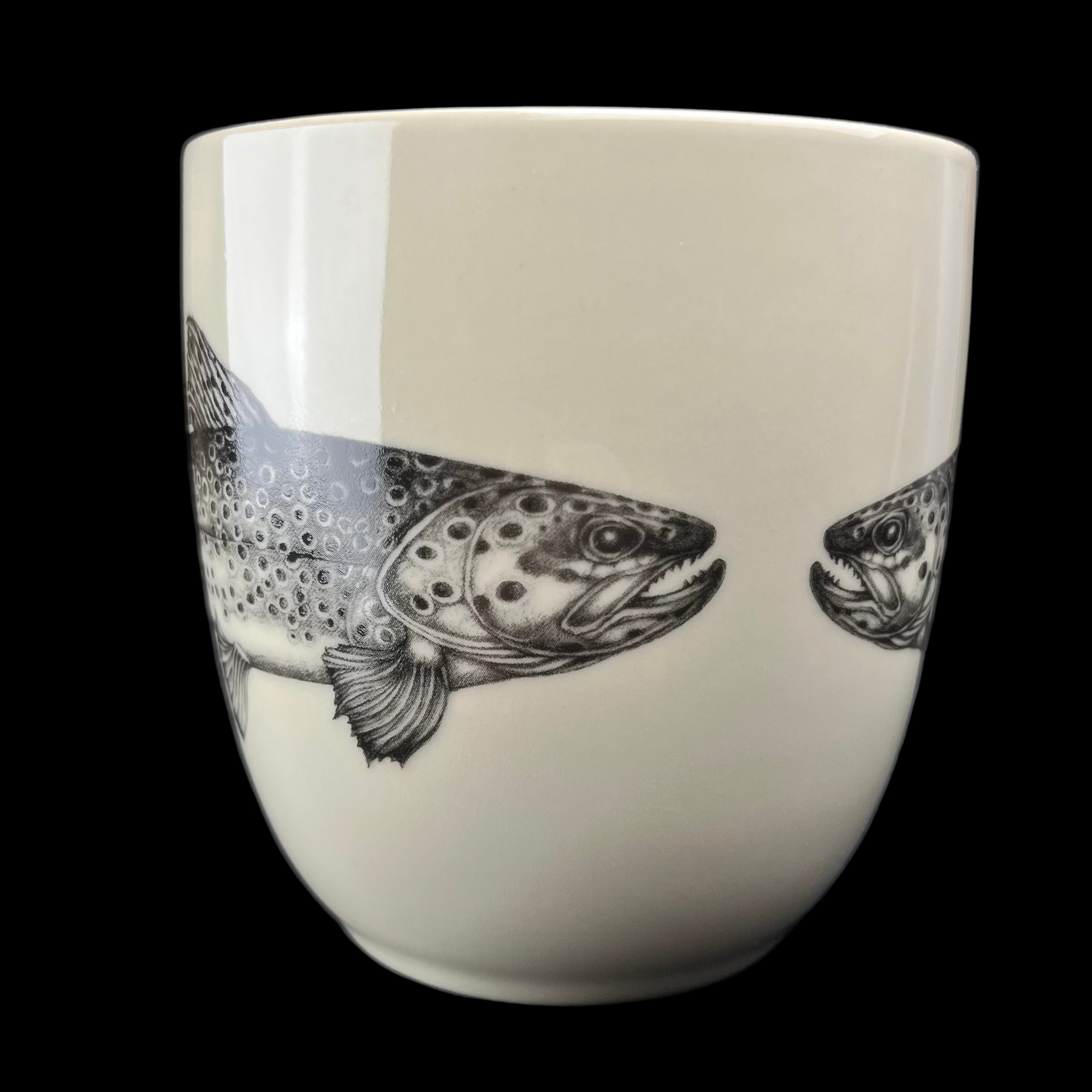 White mug with black and white fish illustration on a dark background