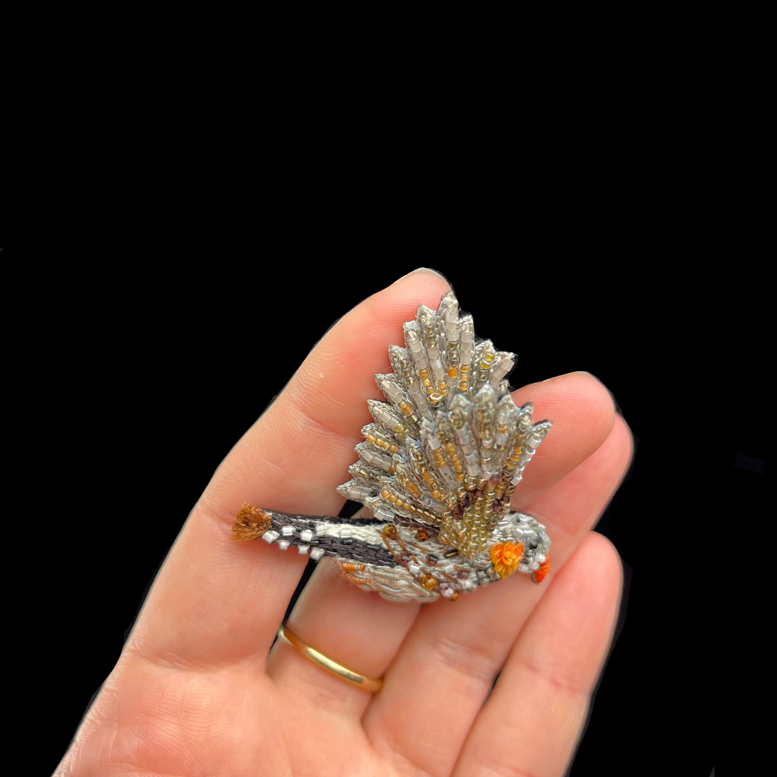 Hand holding a decorative ring with intricate design against a dark background