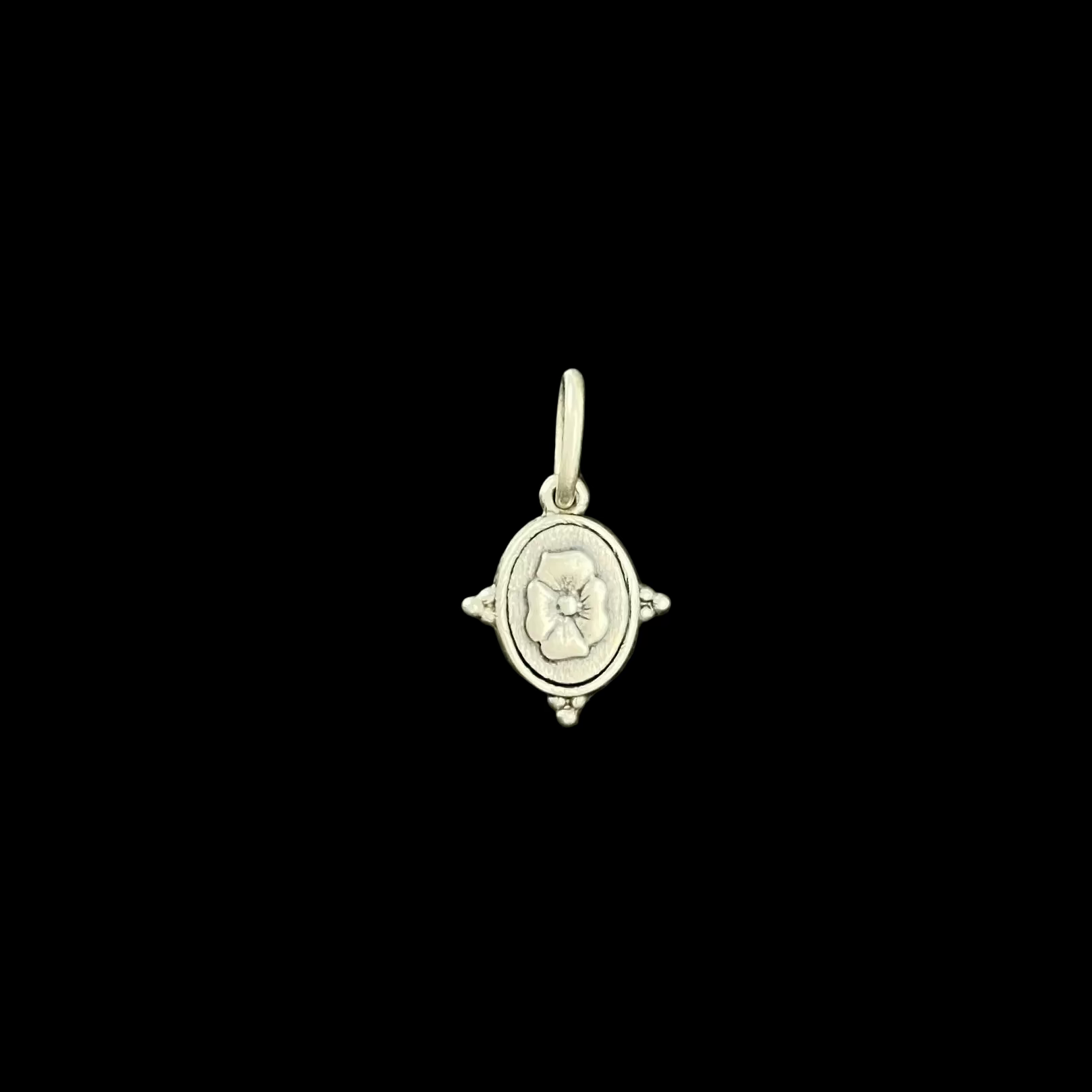 Silver pendant with a floral design on a black textured background