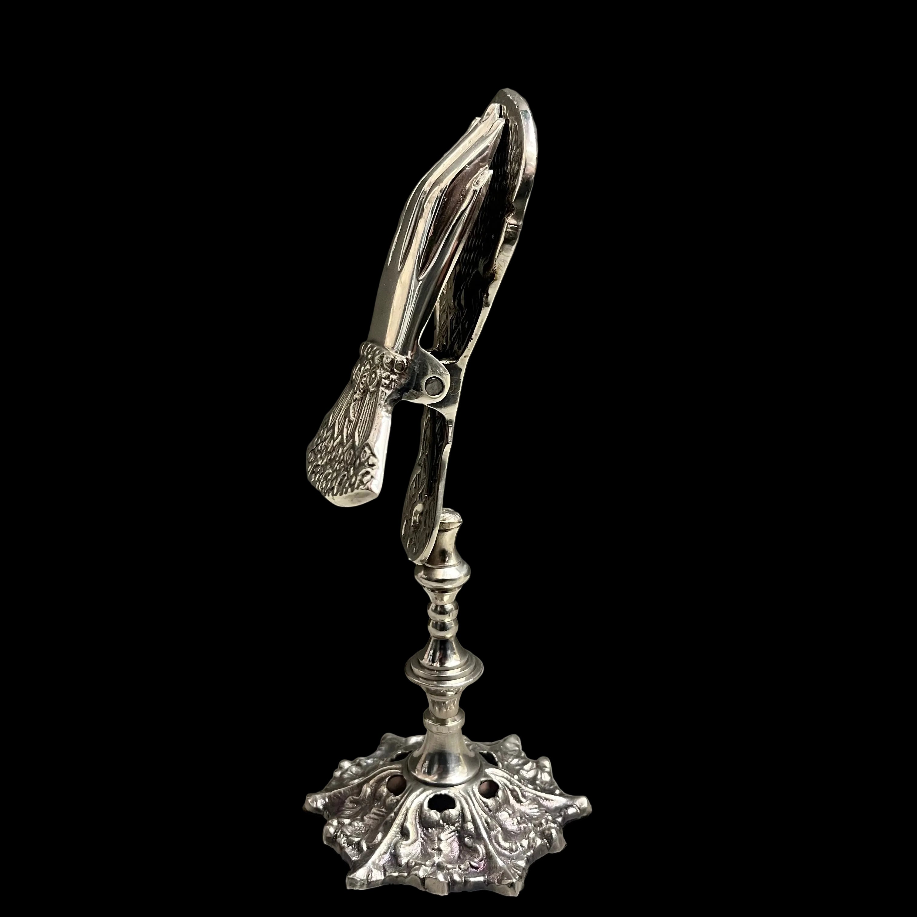 Decorative silver pliers on a stand against a gray background