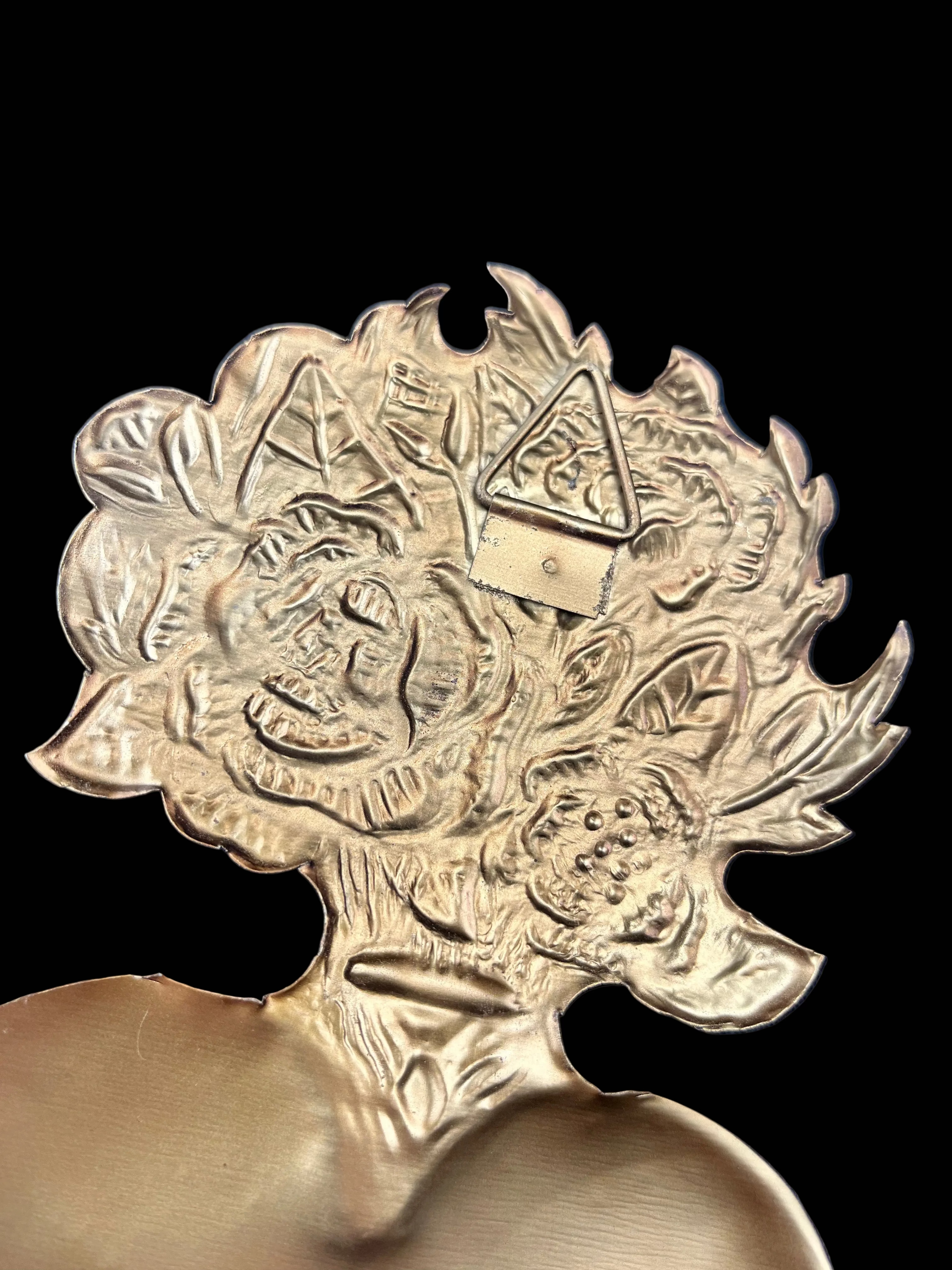 Decorative brass object with intricate designs on a black background