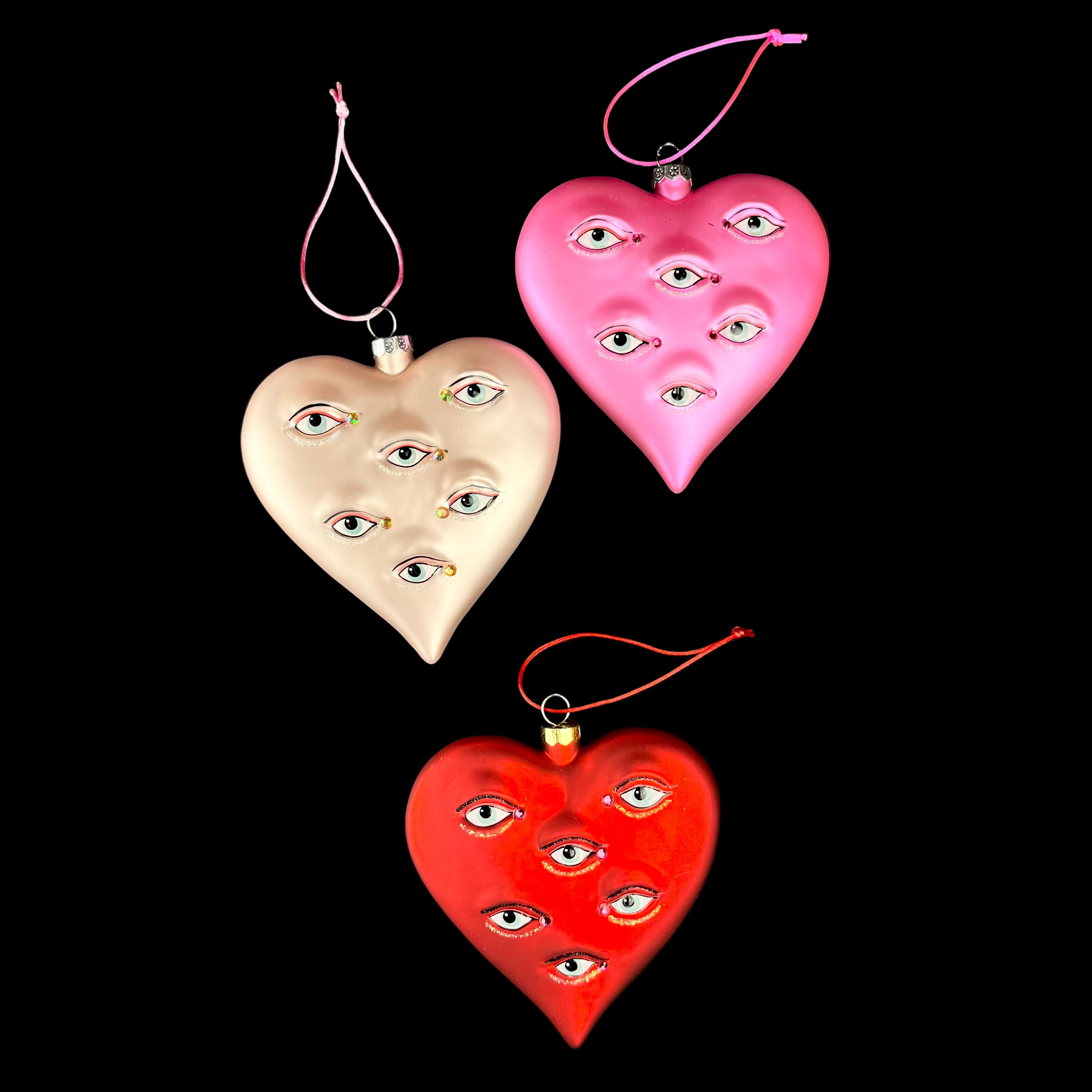 Three heart-shaped decorations with eye patterns on a black background