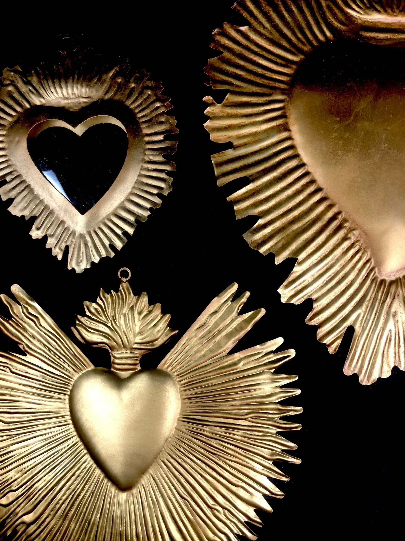 radiating scared heart metal shown on bottom left of a collection of milagros