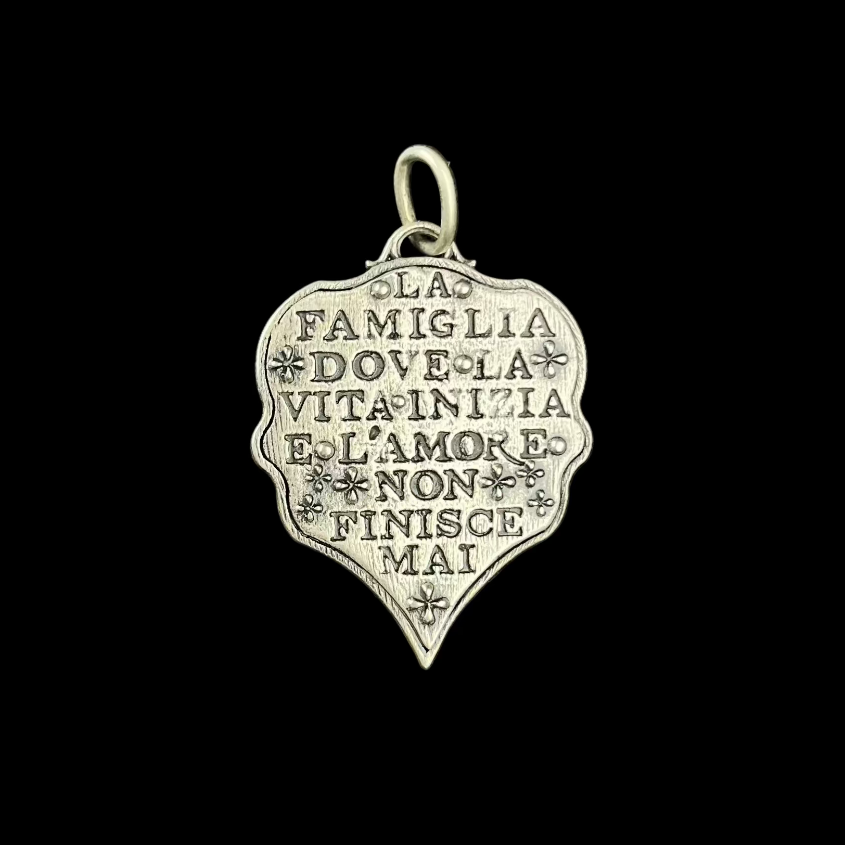 Silver pendant with engraved text on a black background