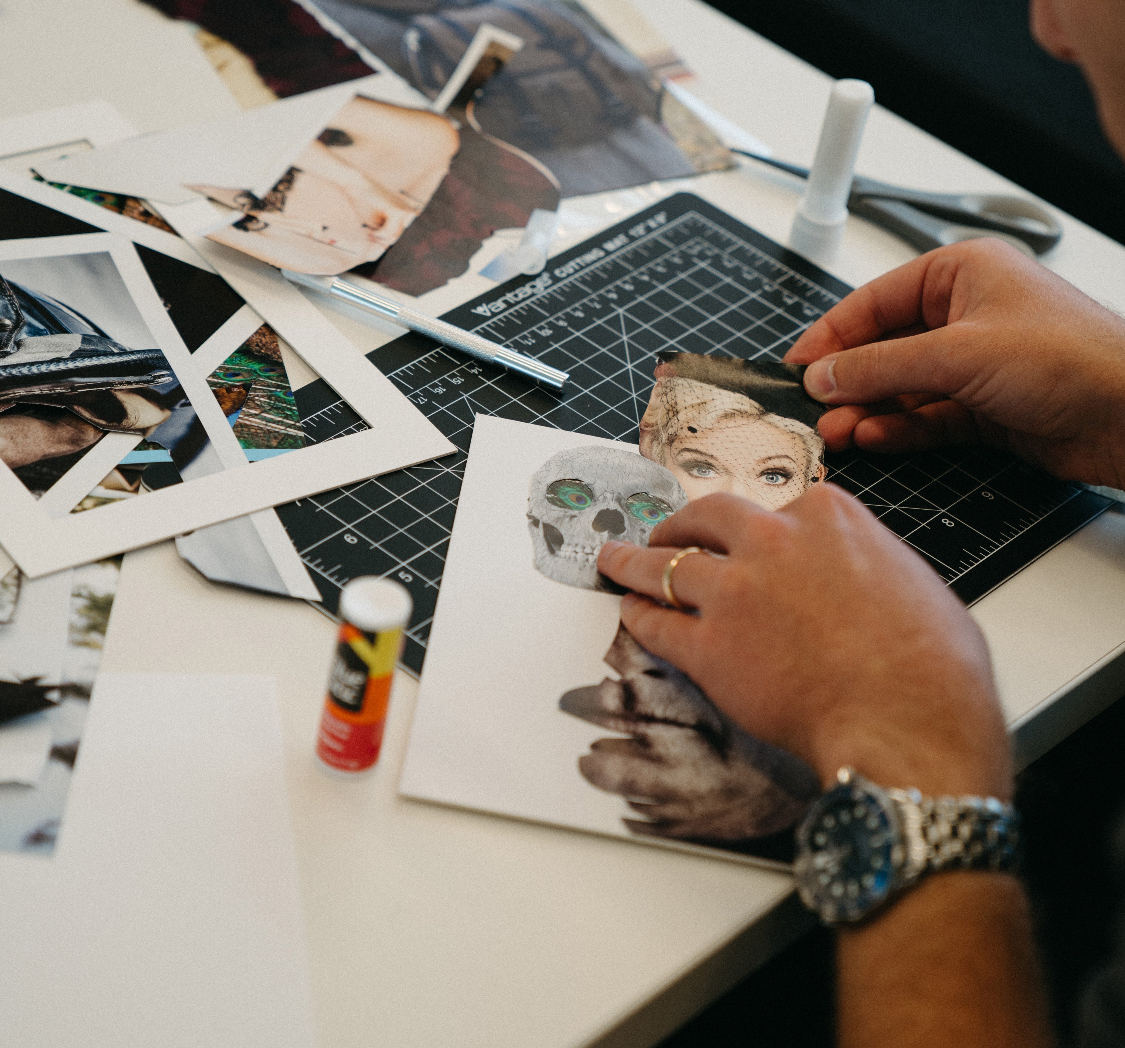 Person working on a craft project with photos and tools on a table