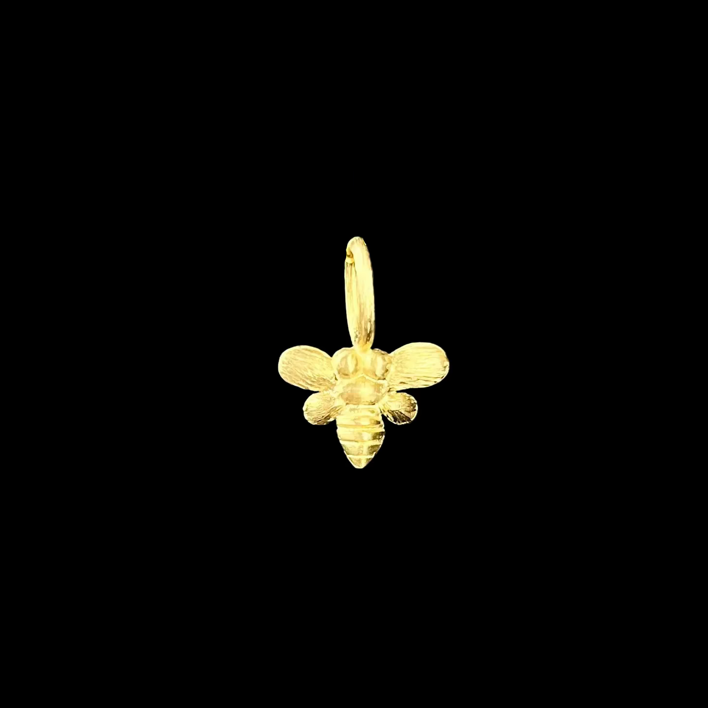 Gold bee-shaped pendant charm on a black background