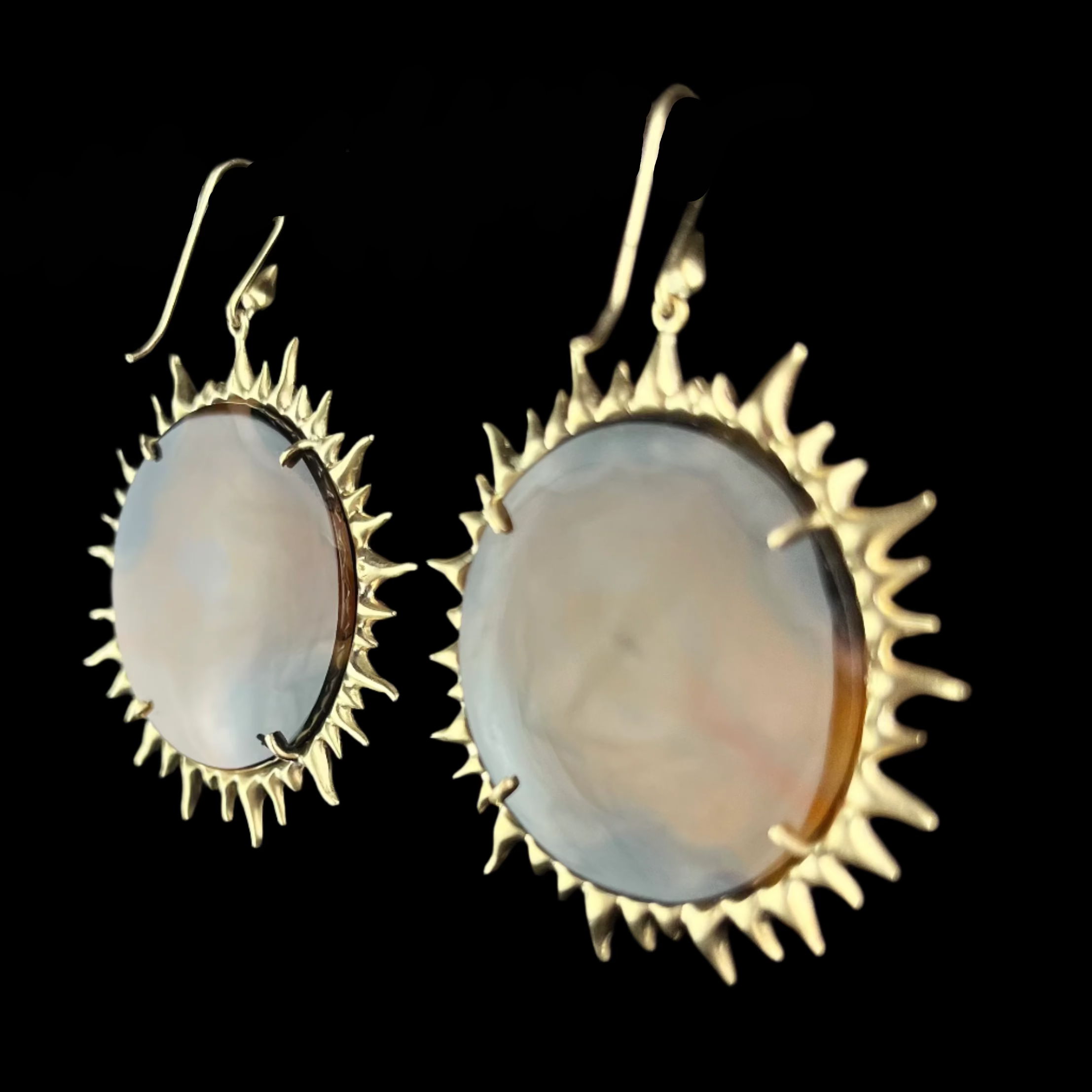Gold-framed earrings with circular stones on a dark background