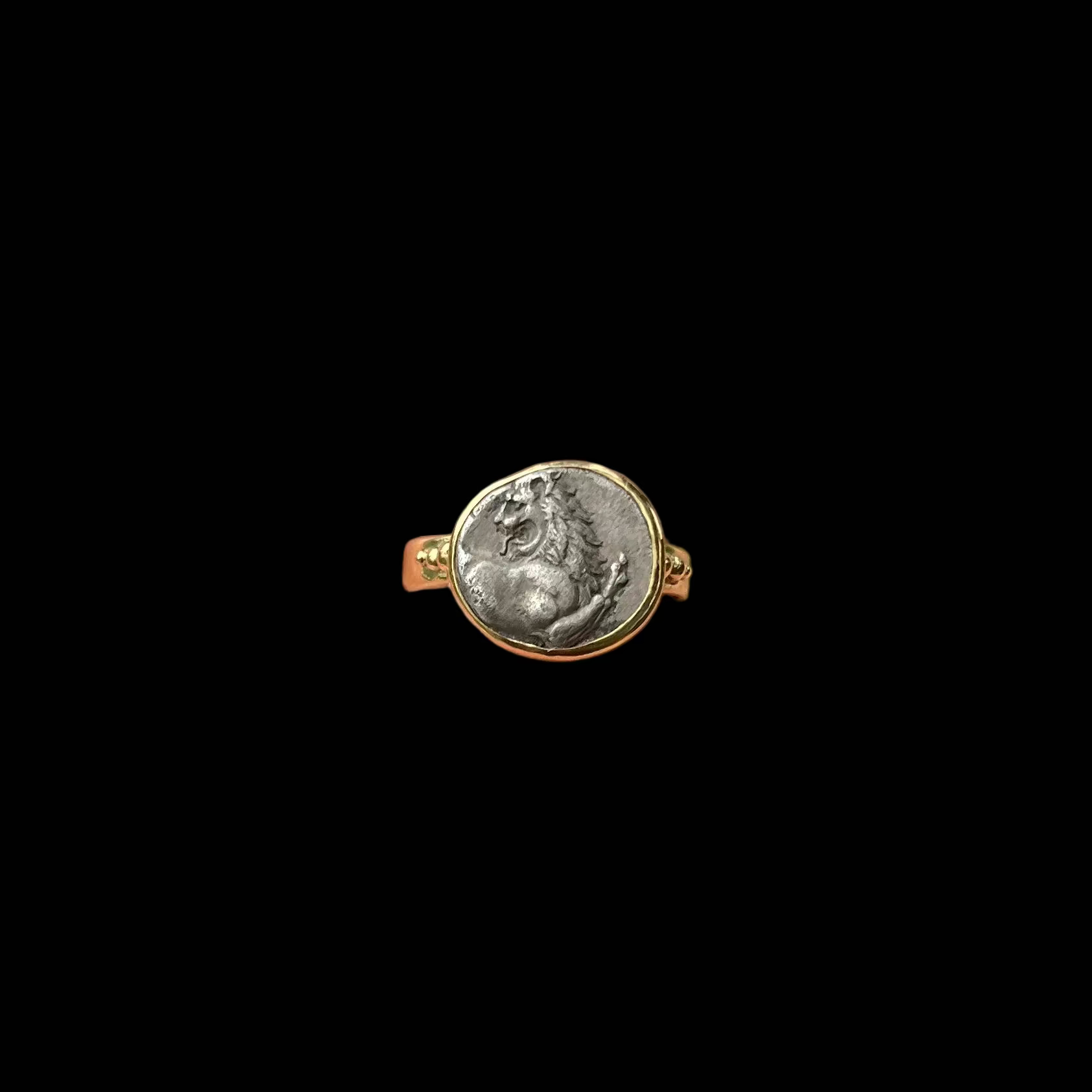 Coin ring set in gold shown on black ackground