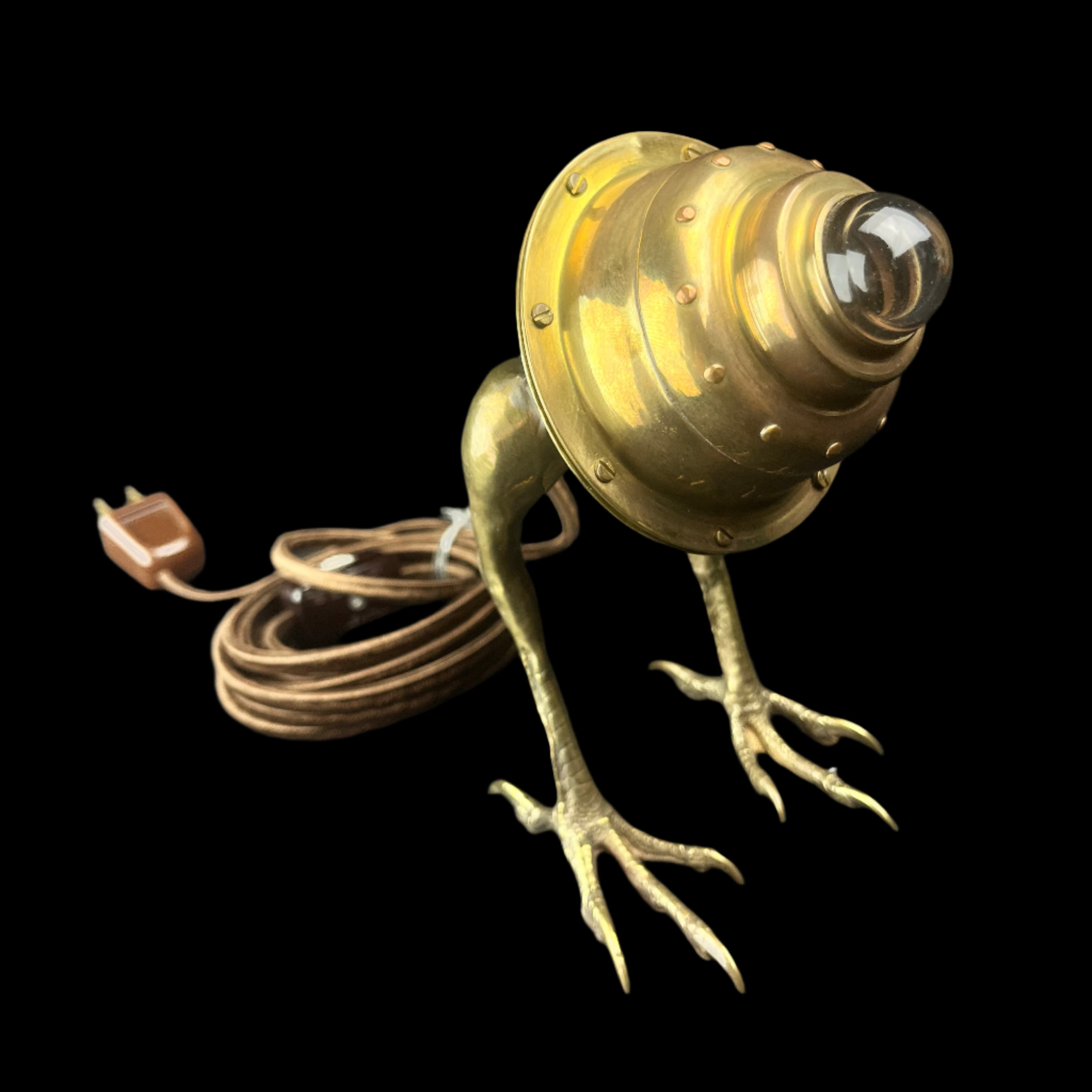 Bronze frog-shaped lamp with a light bulb on a dark surface