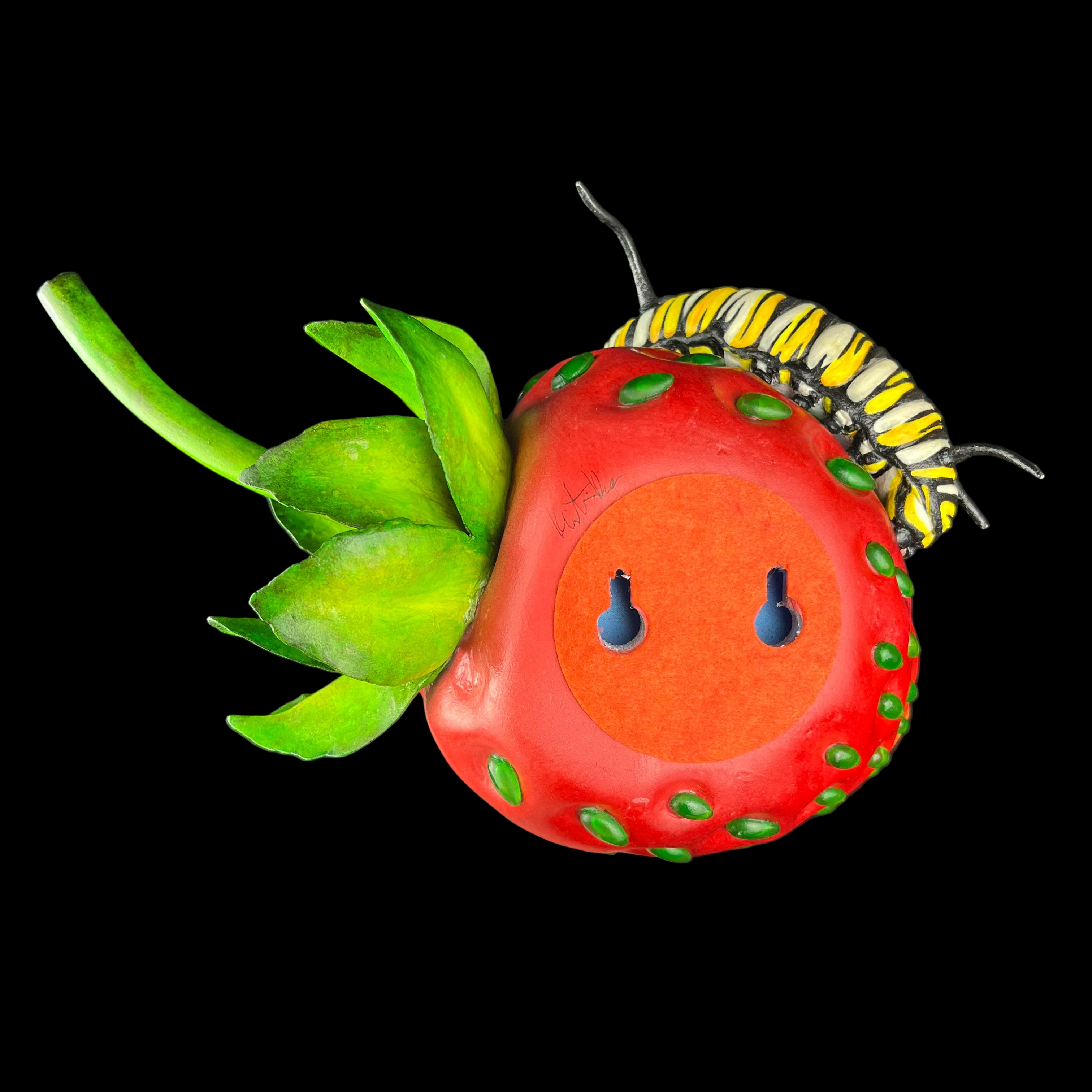 Red strawberry-shaped object with green leaves and a caterpillar on a dark background