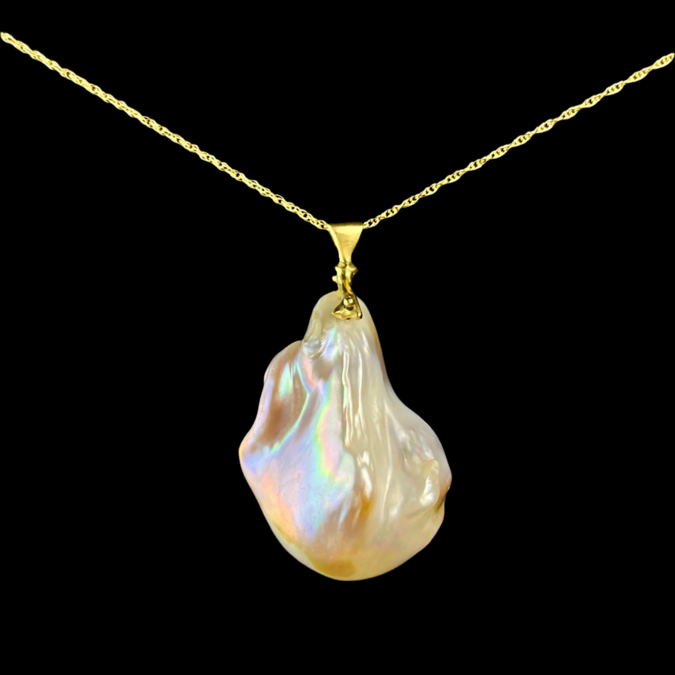 Baroque pearl pendant on a gold chain against a dark background