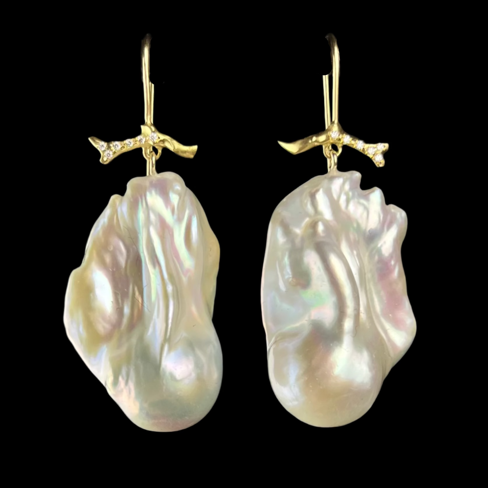 Pair of pearl earrings with gold hooks on a black background
