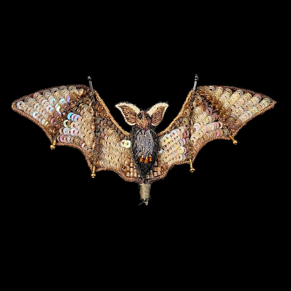 A detailed bat-shaped brooch pin made from iridescent sequins and gold-toned metal.